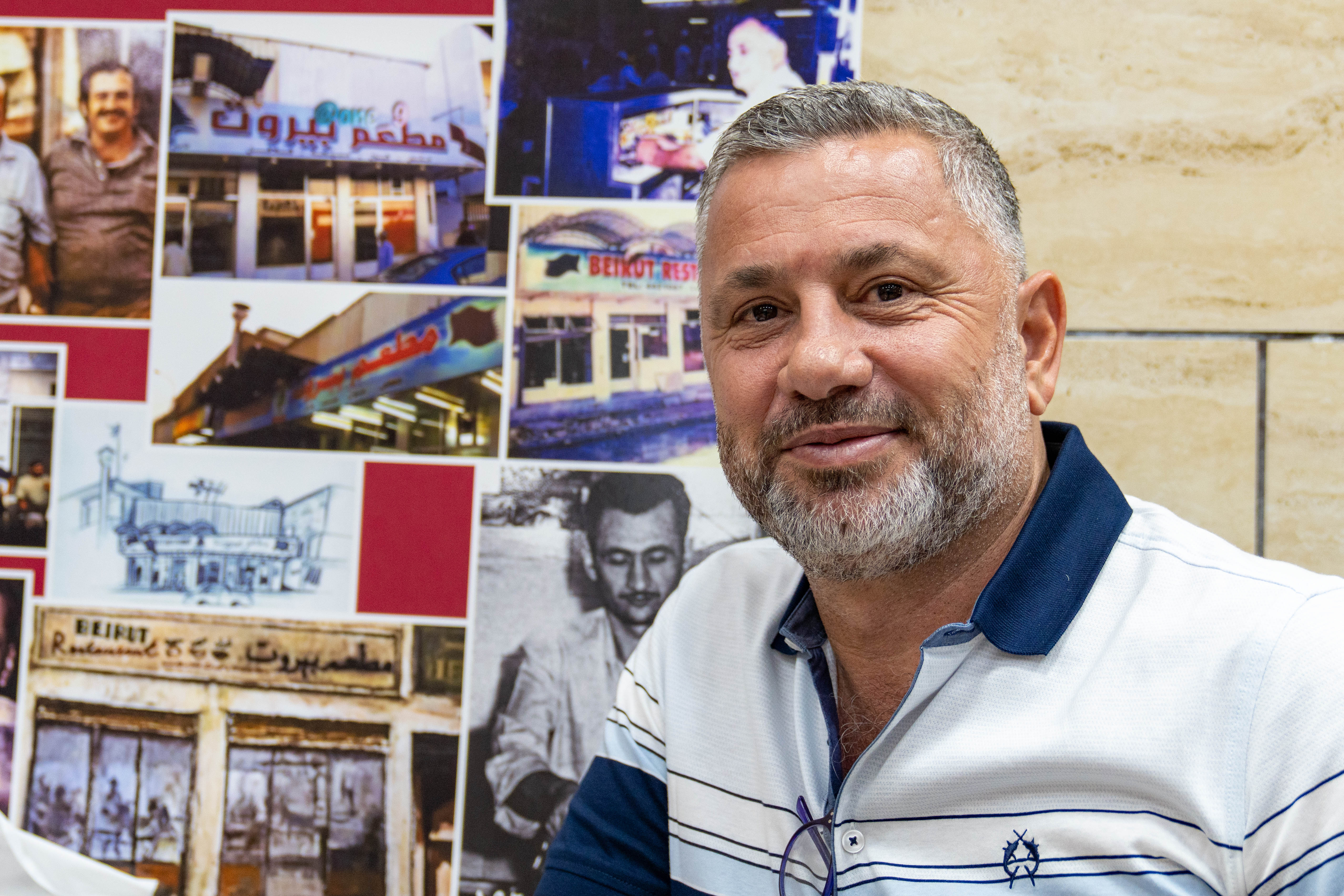 A photo of Ali smiling as he shows old photos of the restaurant and his father and uncle