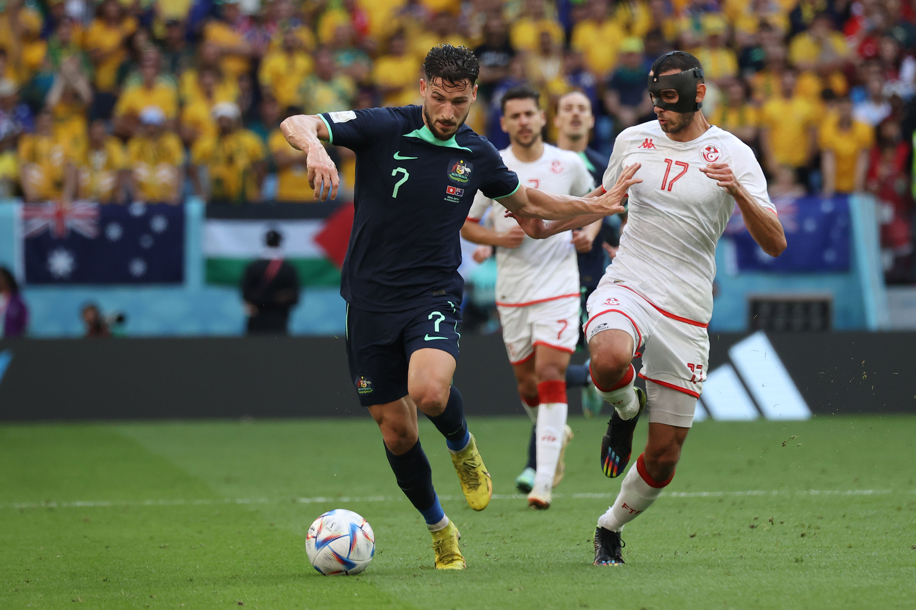 Tunisian and Australian players race for possession of the ball.