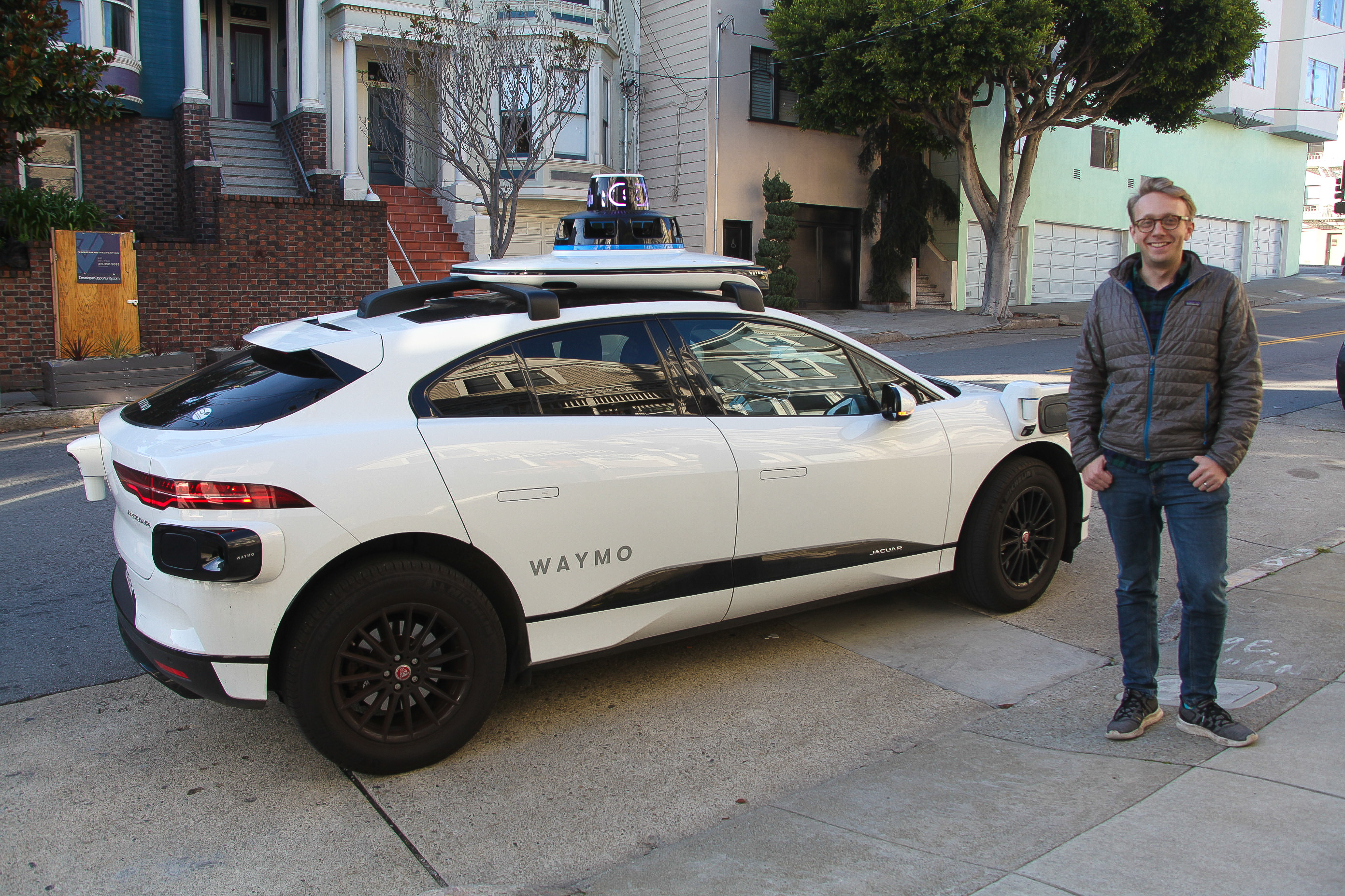 Jack Wanderman stands next to a Waymo vehicle