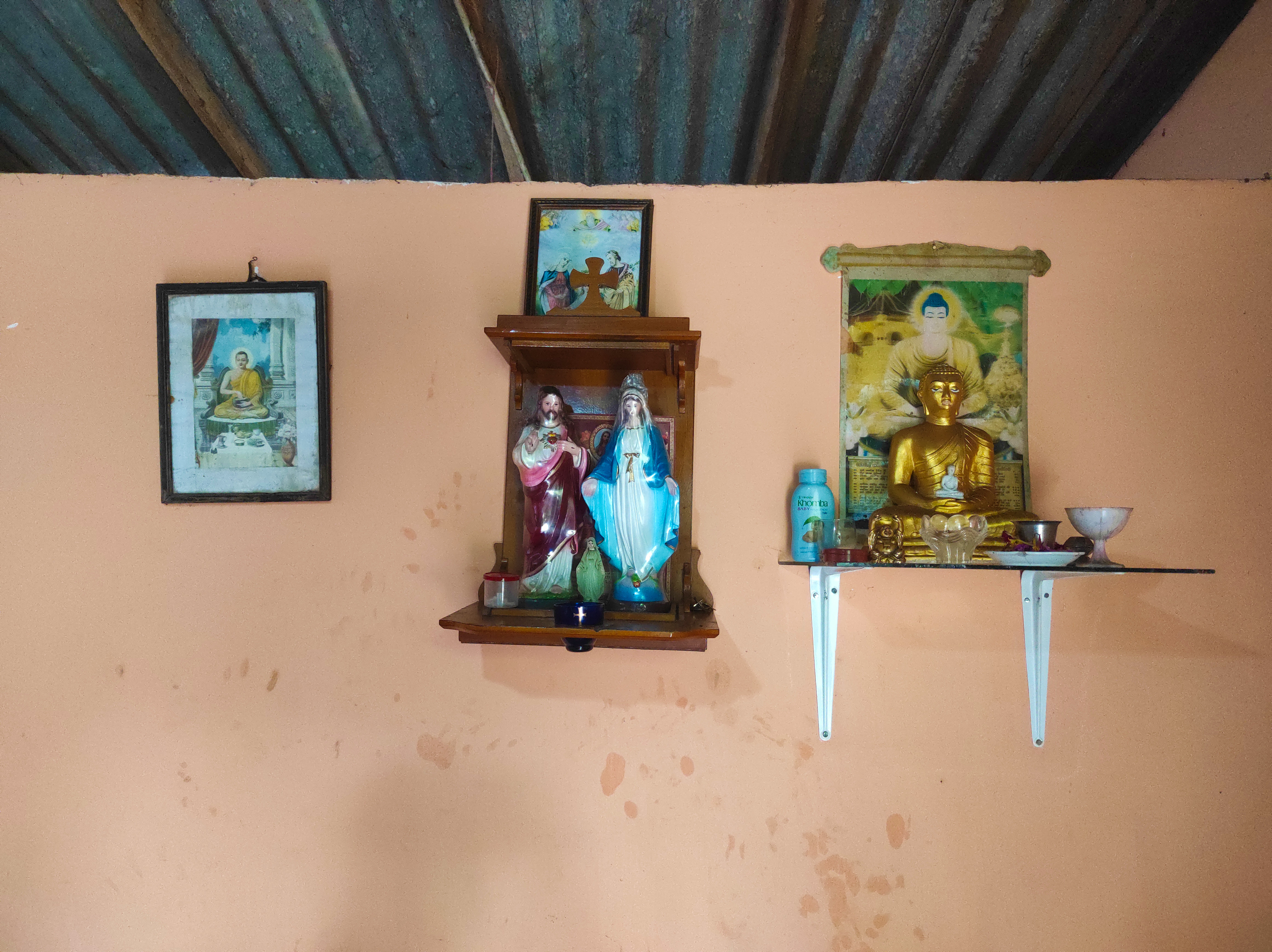 A small Christian altar next to a Buddha statue