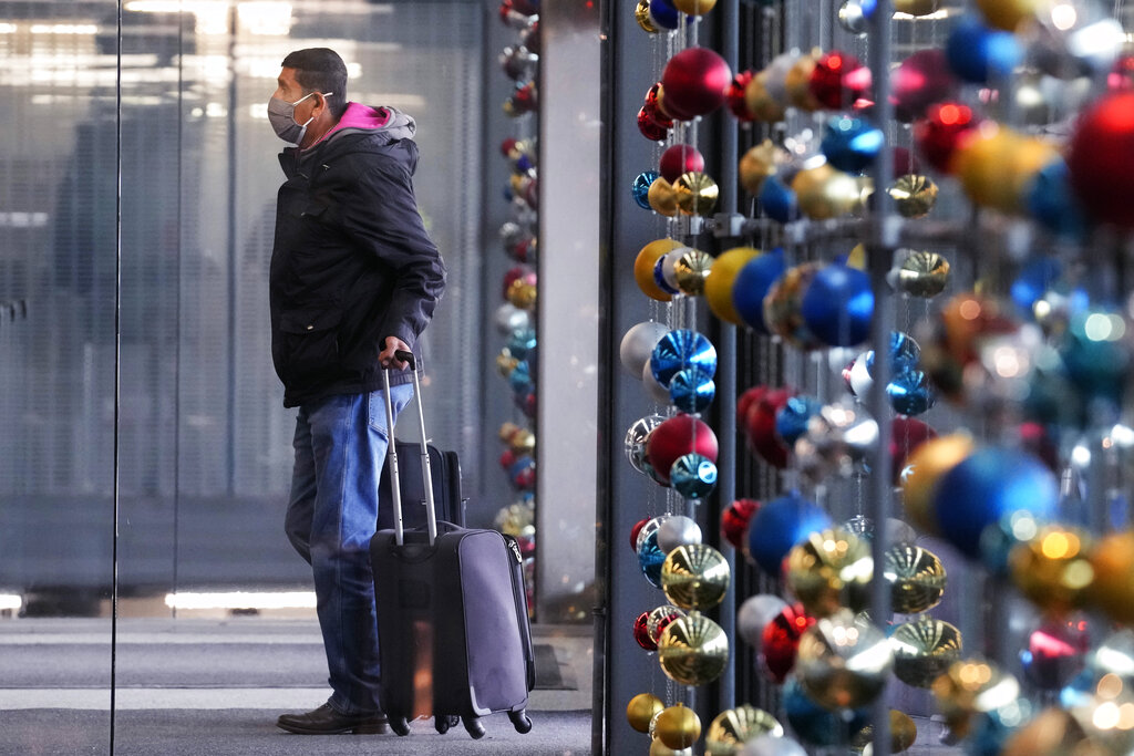 A traveler waits in an airport with holiday ornaments in the background