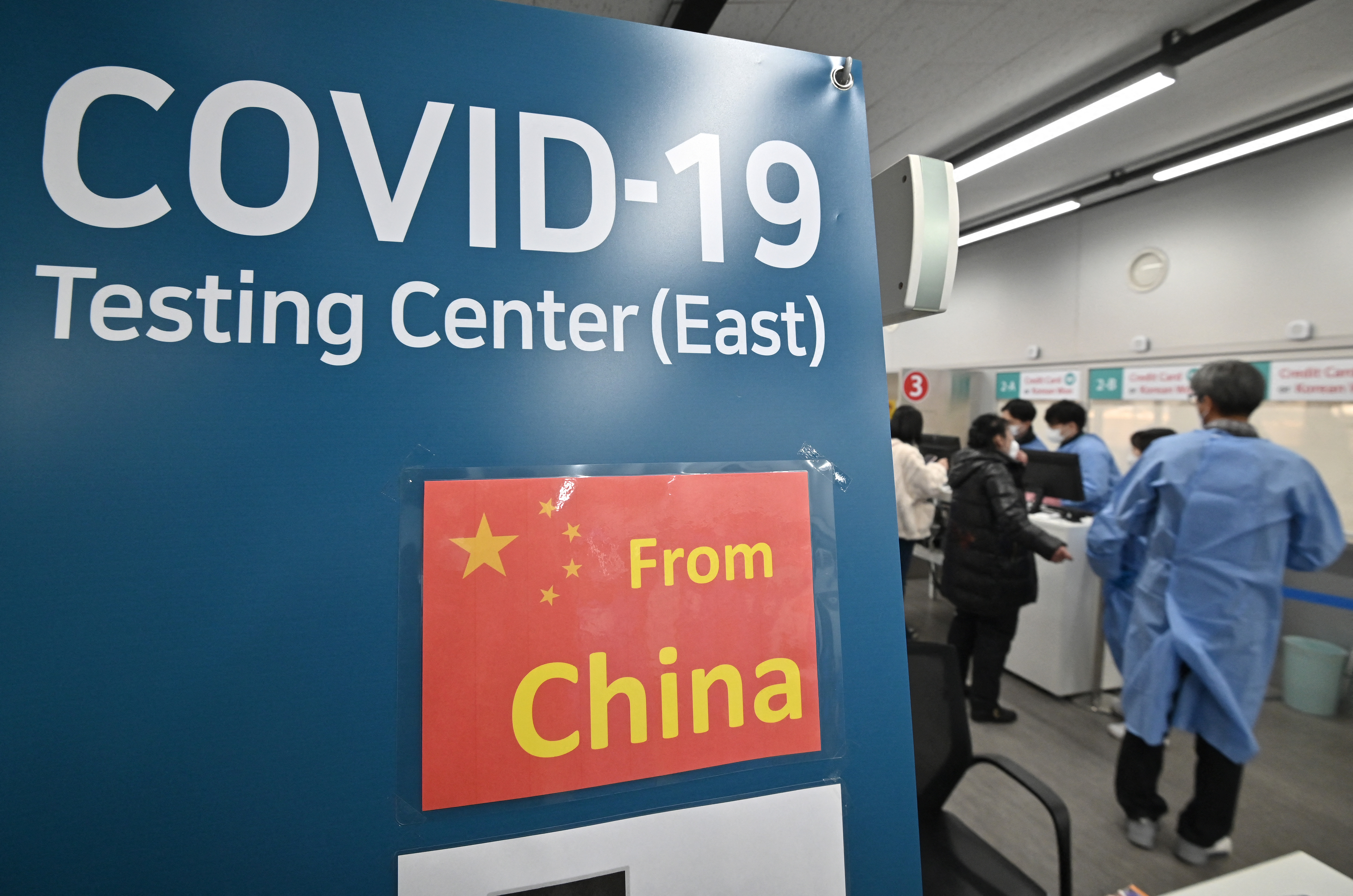 Health workers guide travellers arriving from China at a Covid-19 testing centre at Incheon International Airport, west of Seoul on January 3, 2023. - Around a dozen countries have slapped fresh travel regulations on travellers from China, as the world's most populous nation faces a surge in Covid cases following its decision to relax strict virus restrictions. (Photo by Jung Yeon-je / AFP)