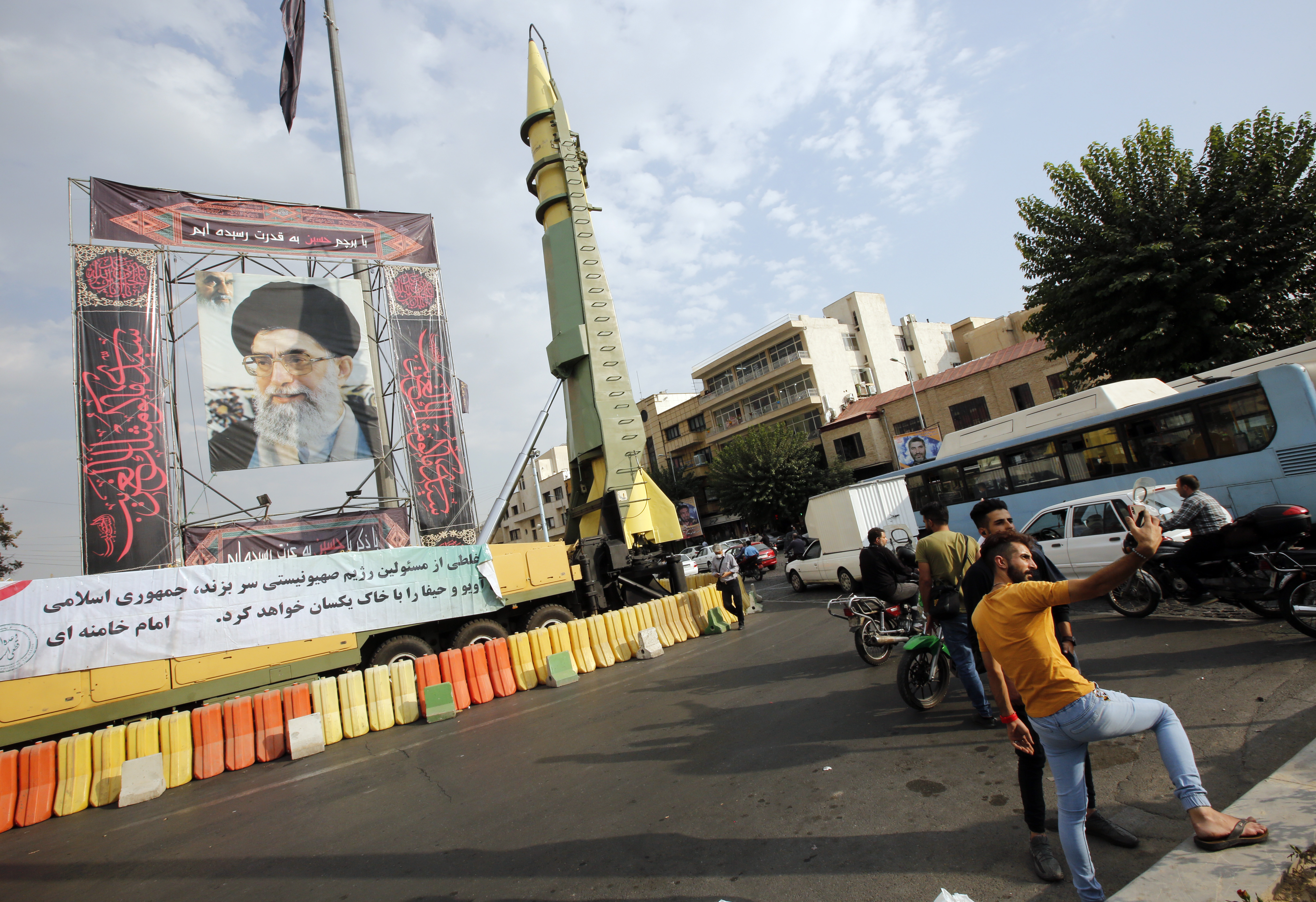 ranians take selfies next to a picture of Iranian supreme leader Ayatollah Ali Khamenei