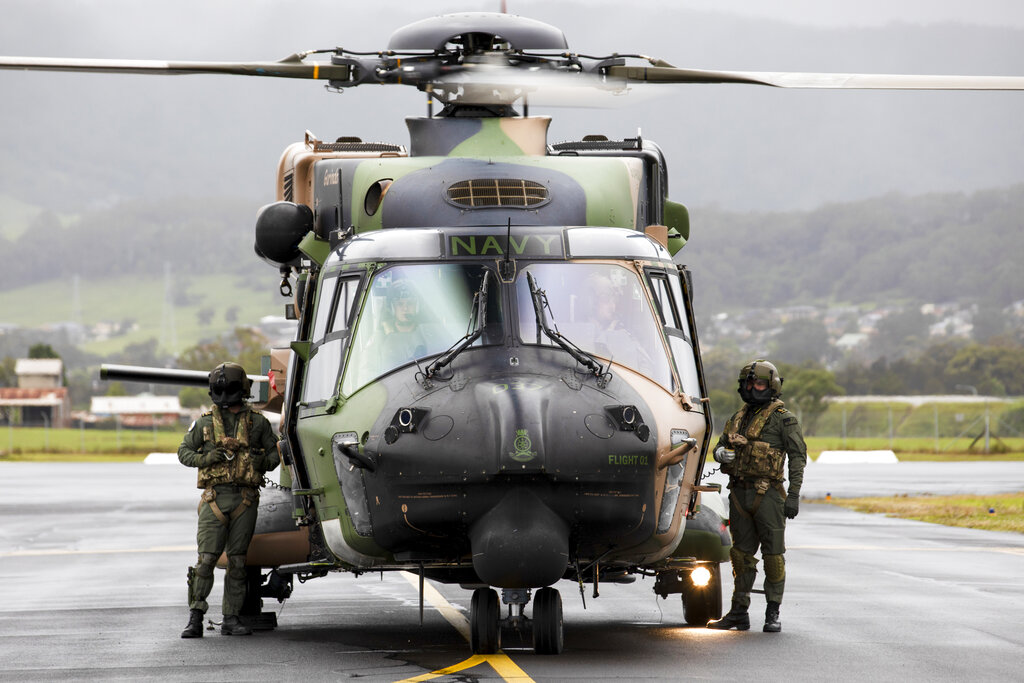 Royal Australian Navy aircrew from the 808 Squadron, stand beside their MRH90 Taipan helicopter in Wollongong, Australia in November 2021. Australia will ditch its fleet of European-designed Taipans and instead buy US Black Hawks [File: Kylie Gibson/ADF via Associated Press Photo