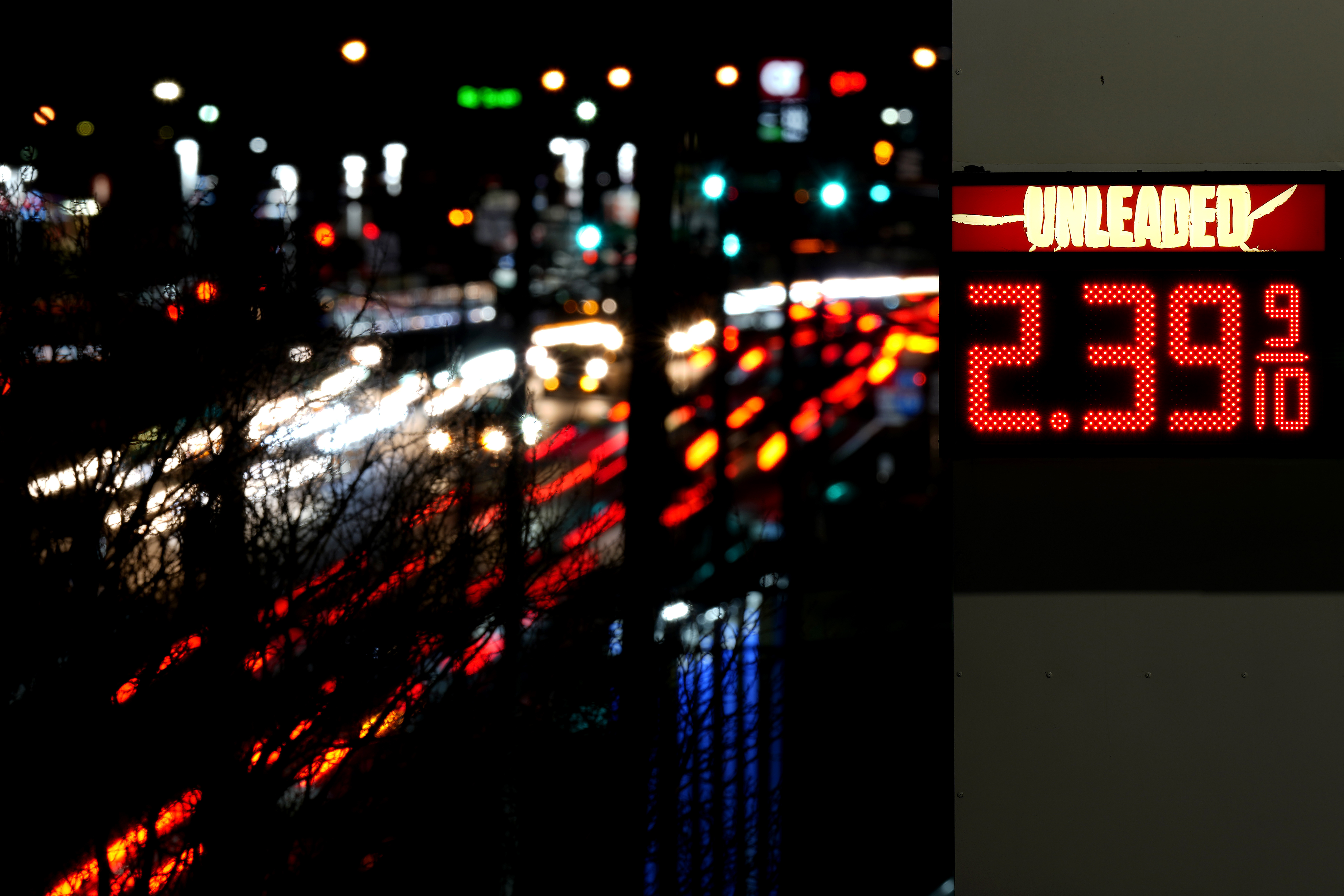 Cars pass a gas station sign displaying the price of regular unleaded gasoline in Benton, MO, US