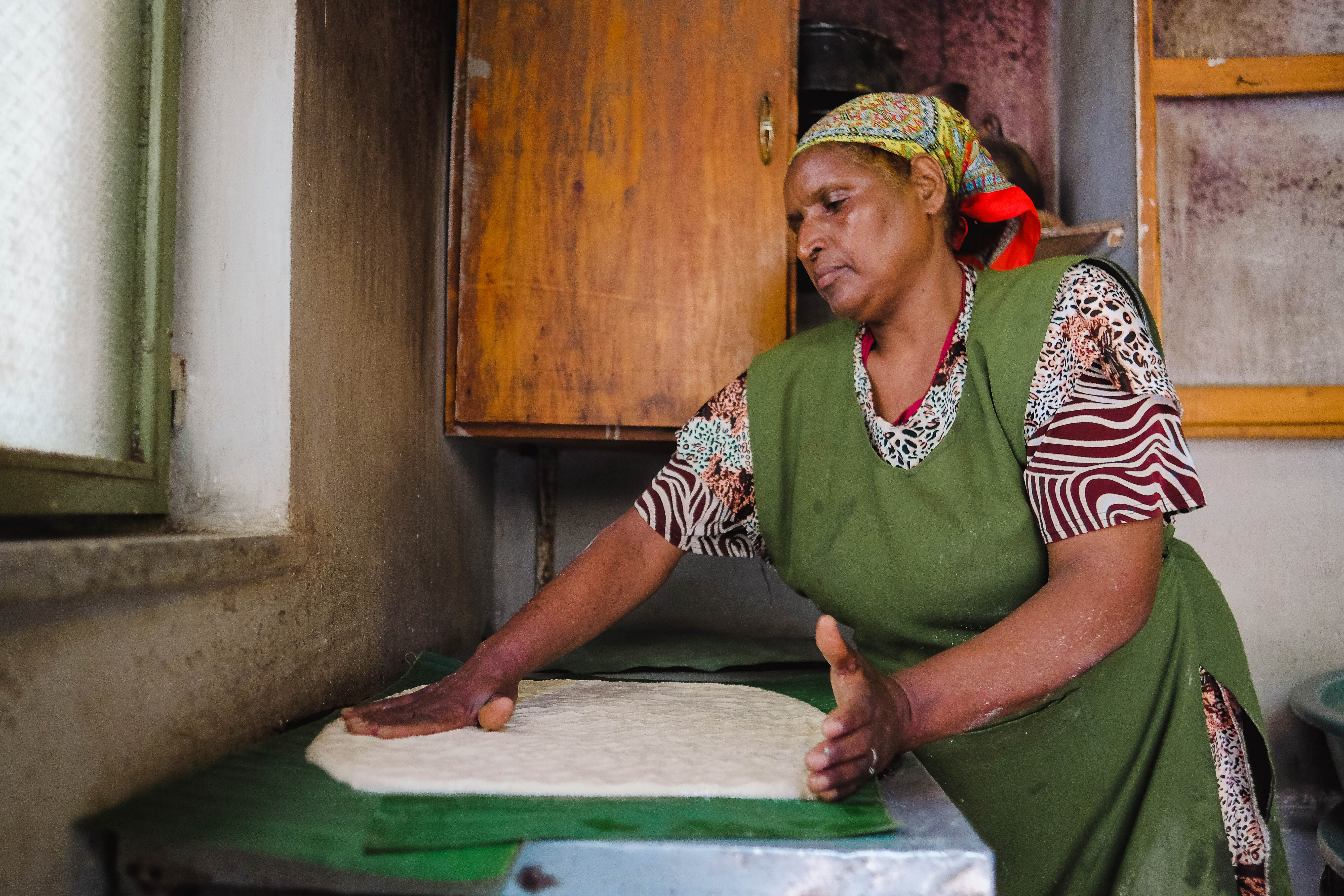 Menteha Hussain flattens a layer of kocho dough on false banana leaves