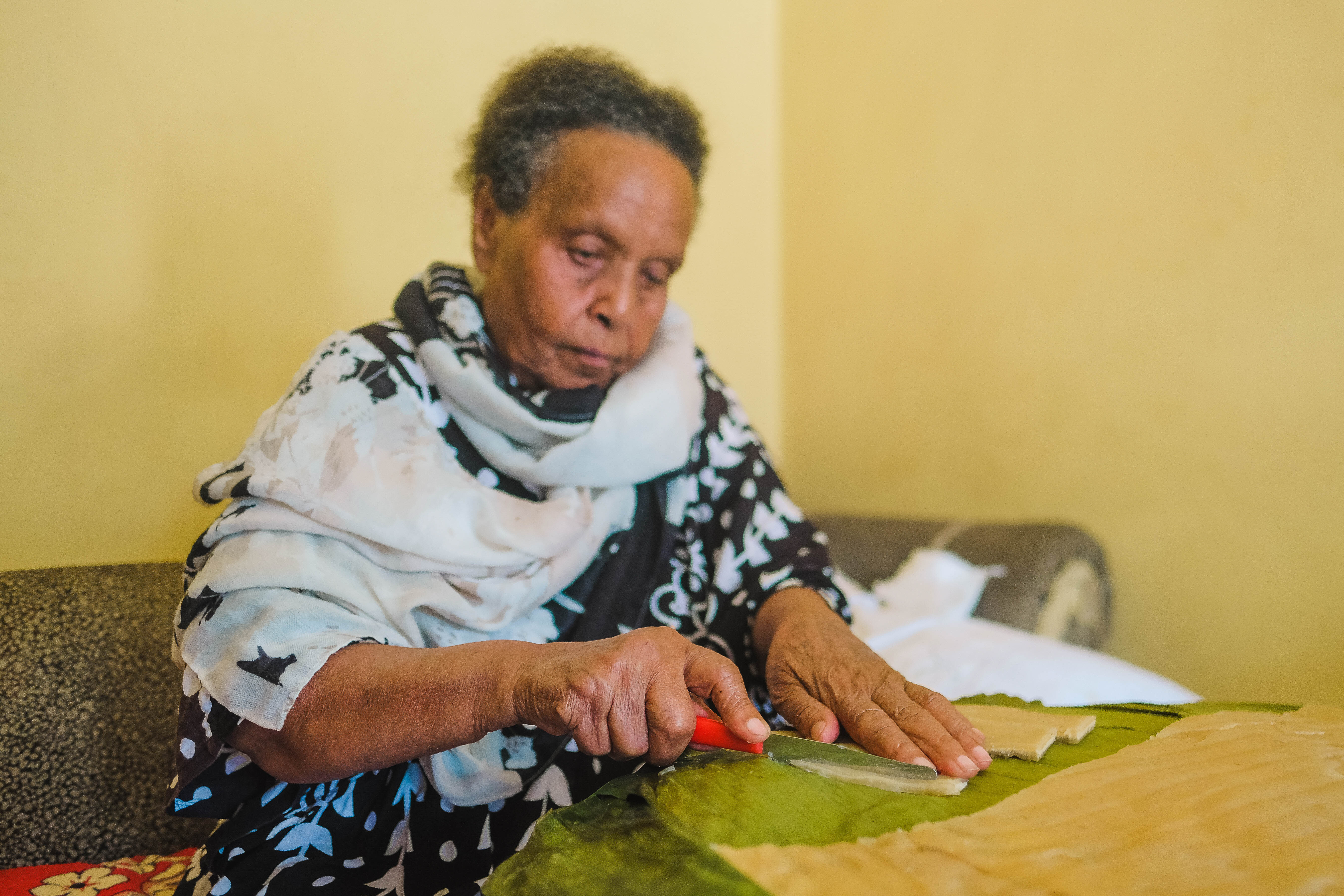 Bekelech sitting down to cut strips of kocho