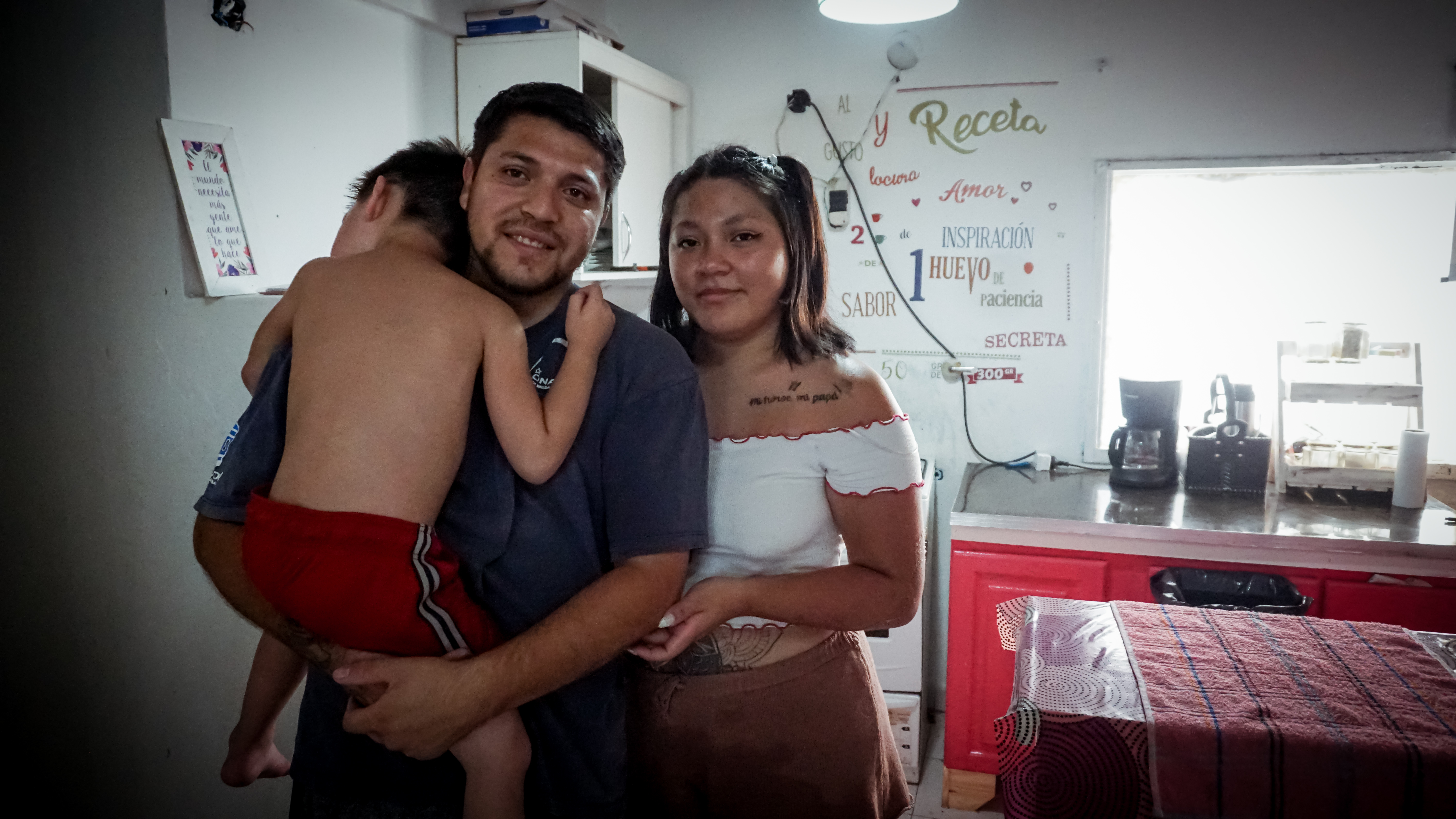 A photo of a man and a woman standing next to each other and the man is holding a child.