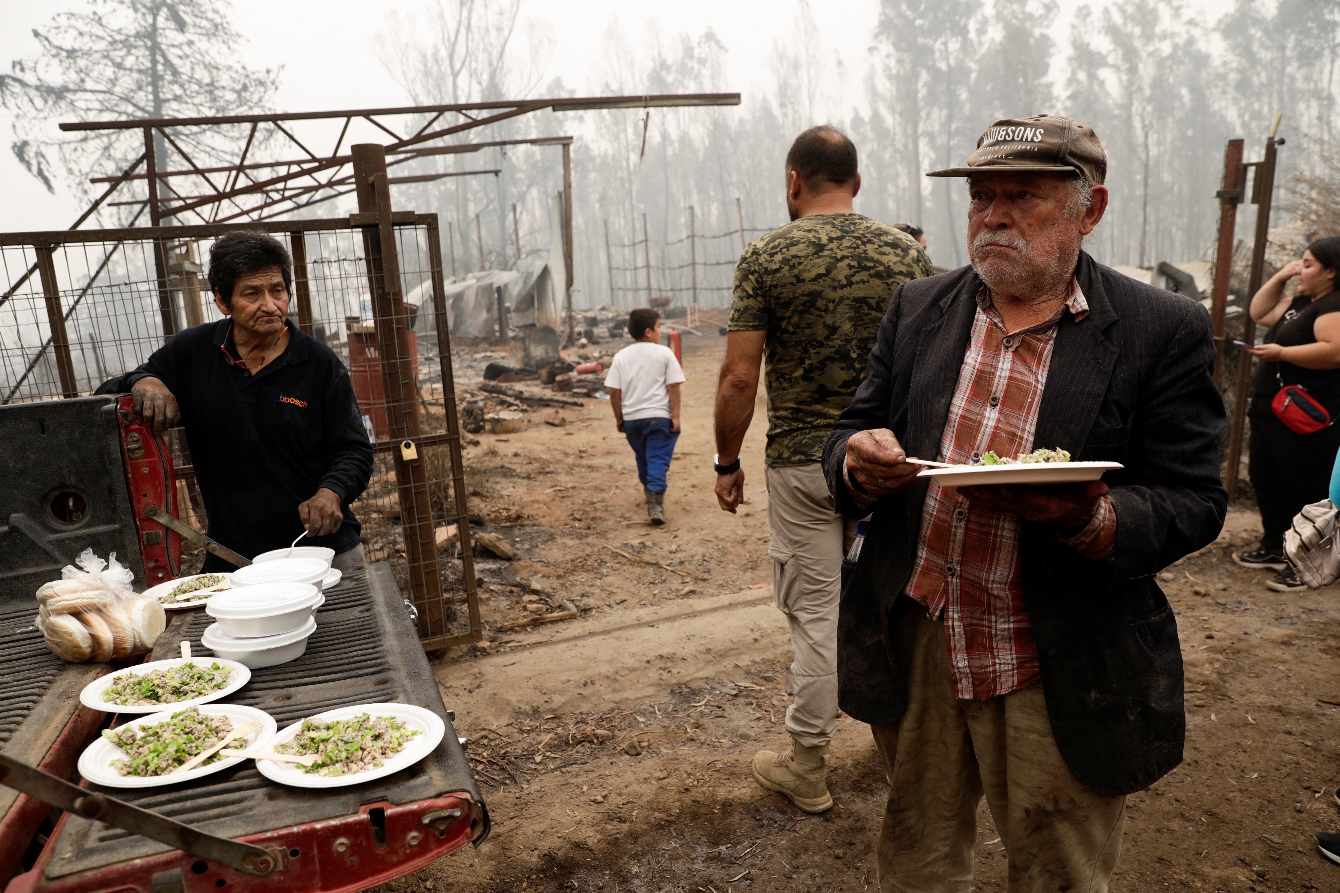 Residents eat after a wildfire burned areas in Santa Juana, Chile