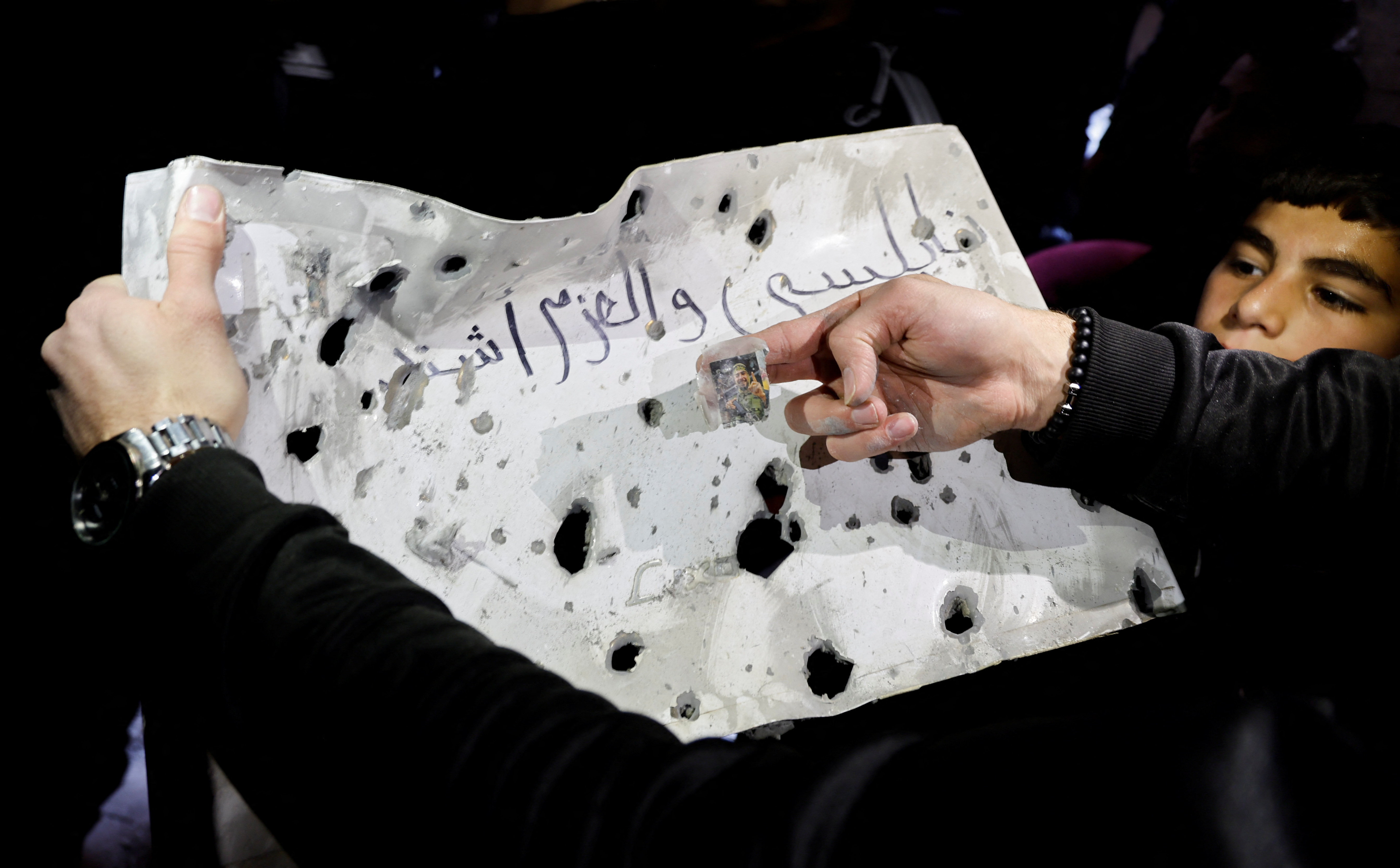 People inspect a metal plate with bullet holes at the site where Israeli troops killed Palestinian gunmen during a raid in Nablus