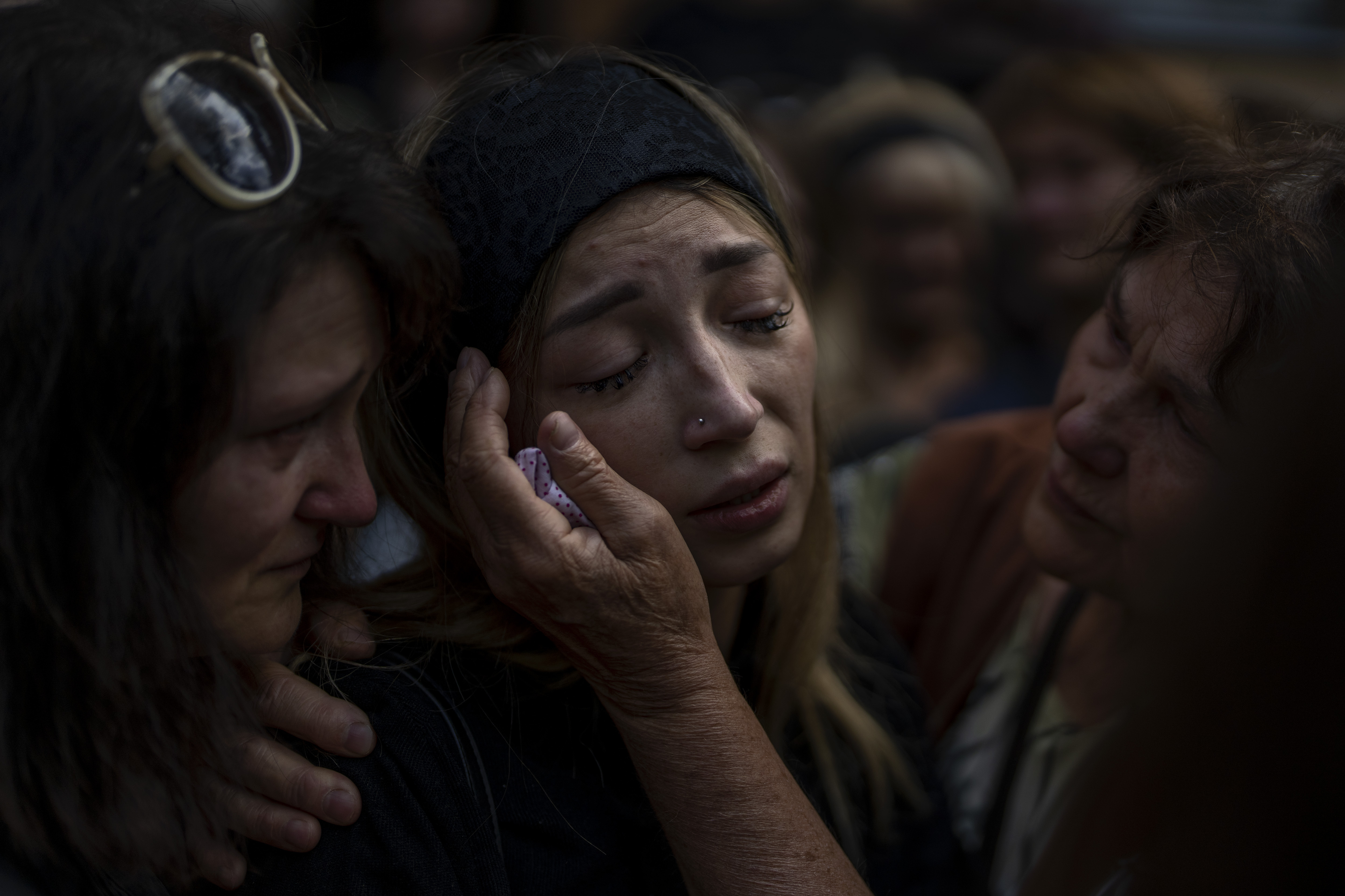 Anastasia Ohrimenko, 26, is comforted by relatives as she cries next to the coffin of her husband
