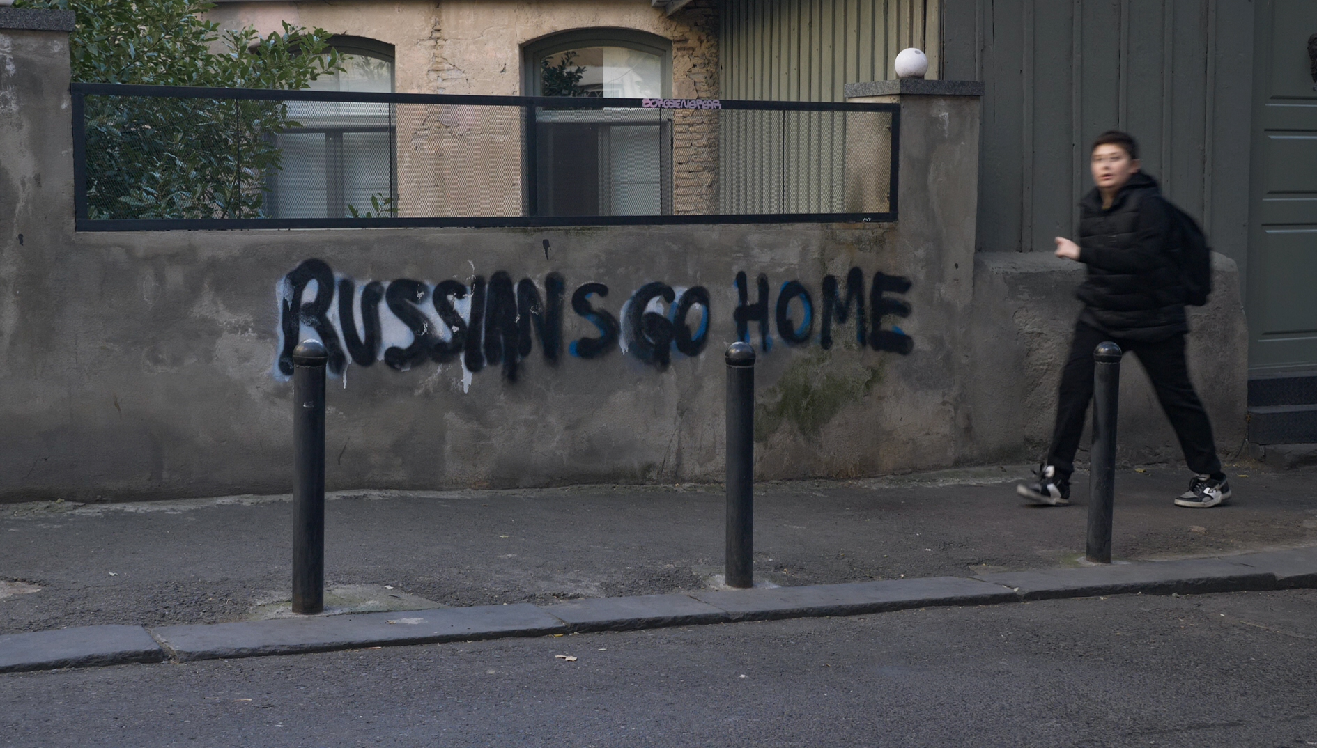 A boy walks past anti-Russian graffiti in Tbilisi, a sign of the resentment directed at the influx of Russians and their country’s full-scale invasion of Ukraine