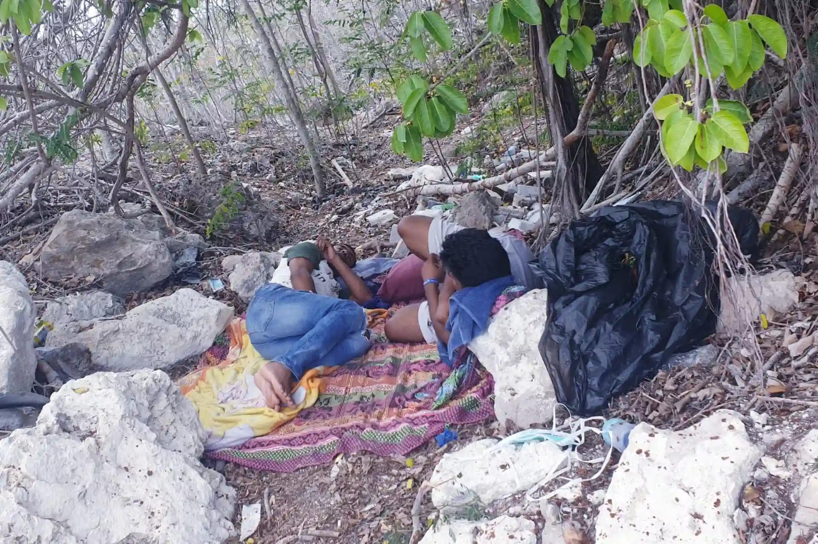 Mohammad Shofigul Islam and Mohammad Kaium, lying on the ground under some brush, have stitched their lips shut to protest their detention on the island nation of Nauru for almost a decade. {Courtesy of Mohammad Shofiqul) 