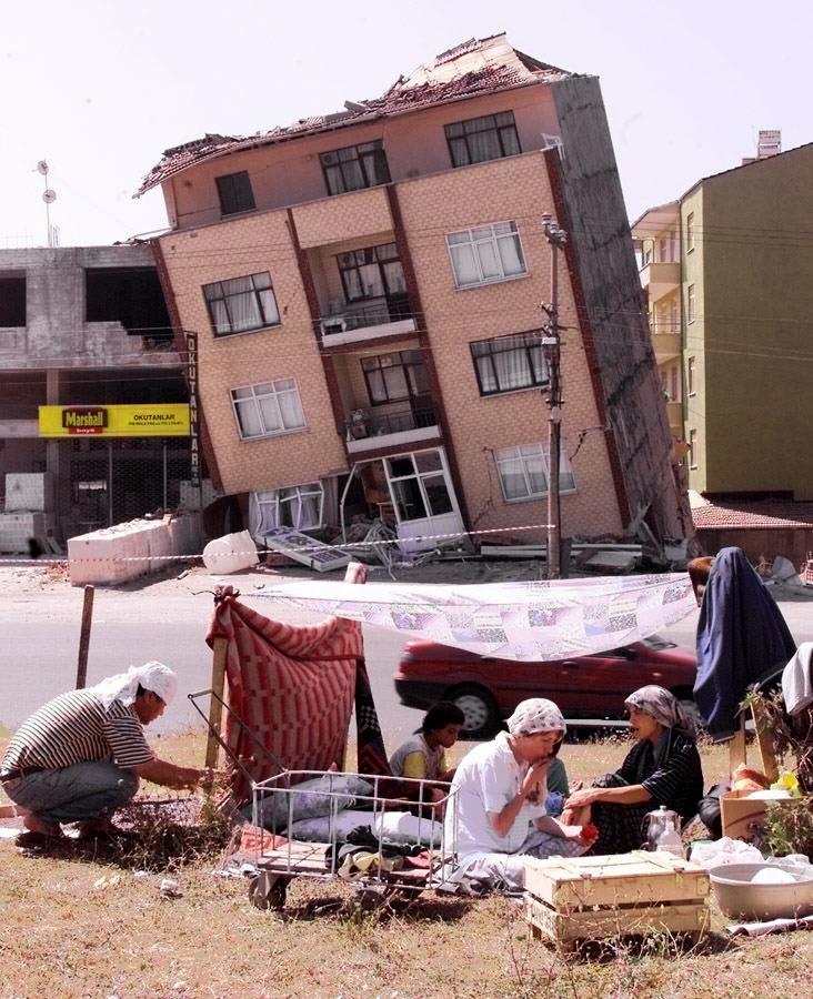 A family camps 18 August 1999 in front of a wrecked house on one of the main avenues of the town of Izmit on the Marmara Sea, where the death toll rose to at least 2,000 following the 17 August 1999 earthquake, measuring 7.4 on the open-ended Richter scale. The Turkish government crisis ceenter counted 18 August 1999 3,741 dead and more than 17,000 in the central and western Anatolian provinces. (ELECTRONIC IMAGE) (Photo by PIERRE VERDY / AFP)