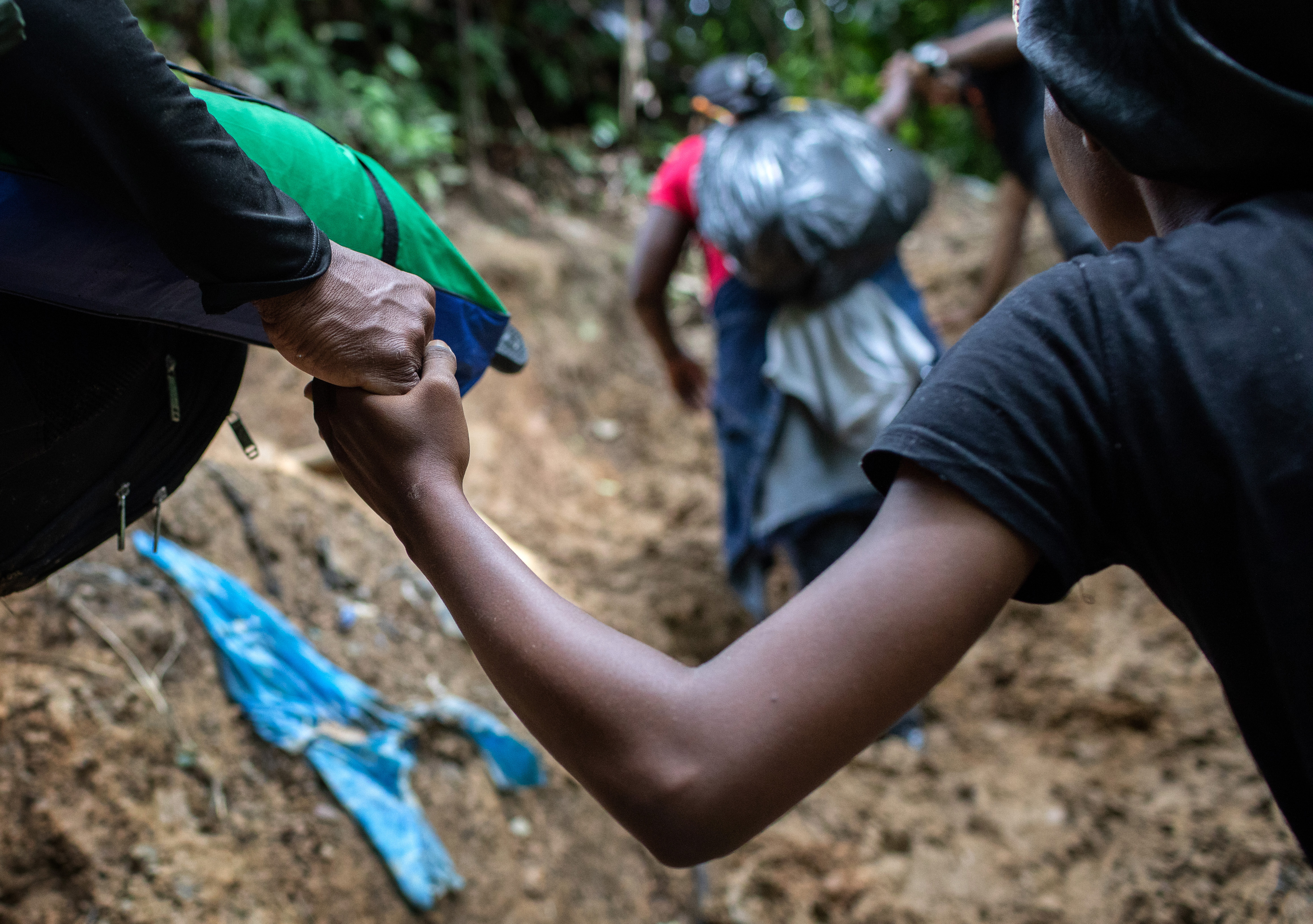 A Colombian guide helps a Haitian woman up a steep mountain slope near Colombia's border with Panama on October 20, 2021 in the Darien Gap, Colombia.