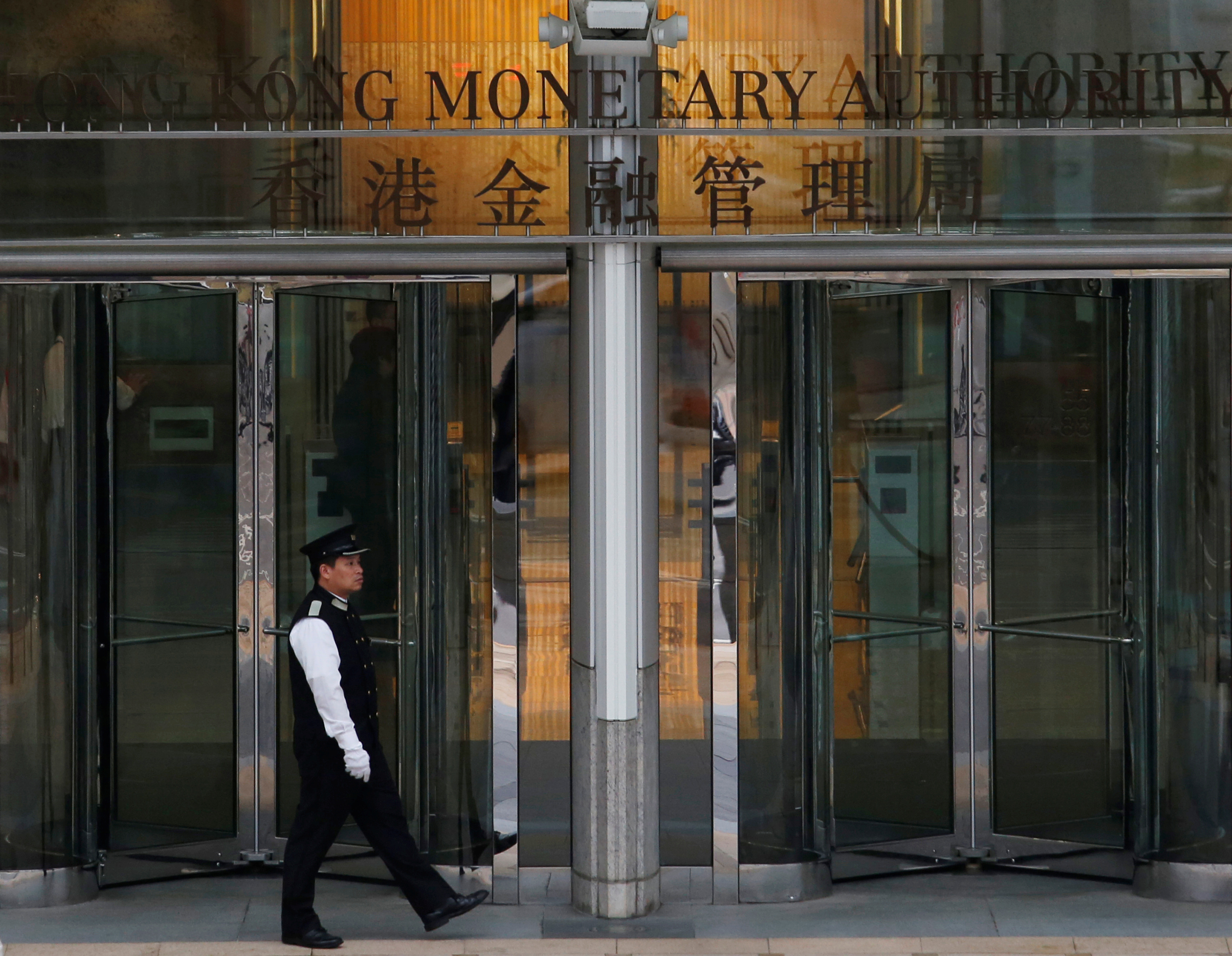 An MAN walks outside the entrance to Hong Kong Monetary Authority in Hong Kong, China.