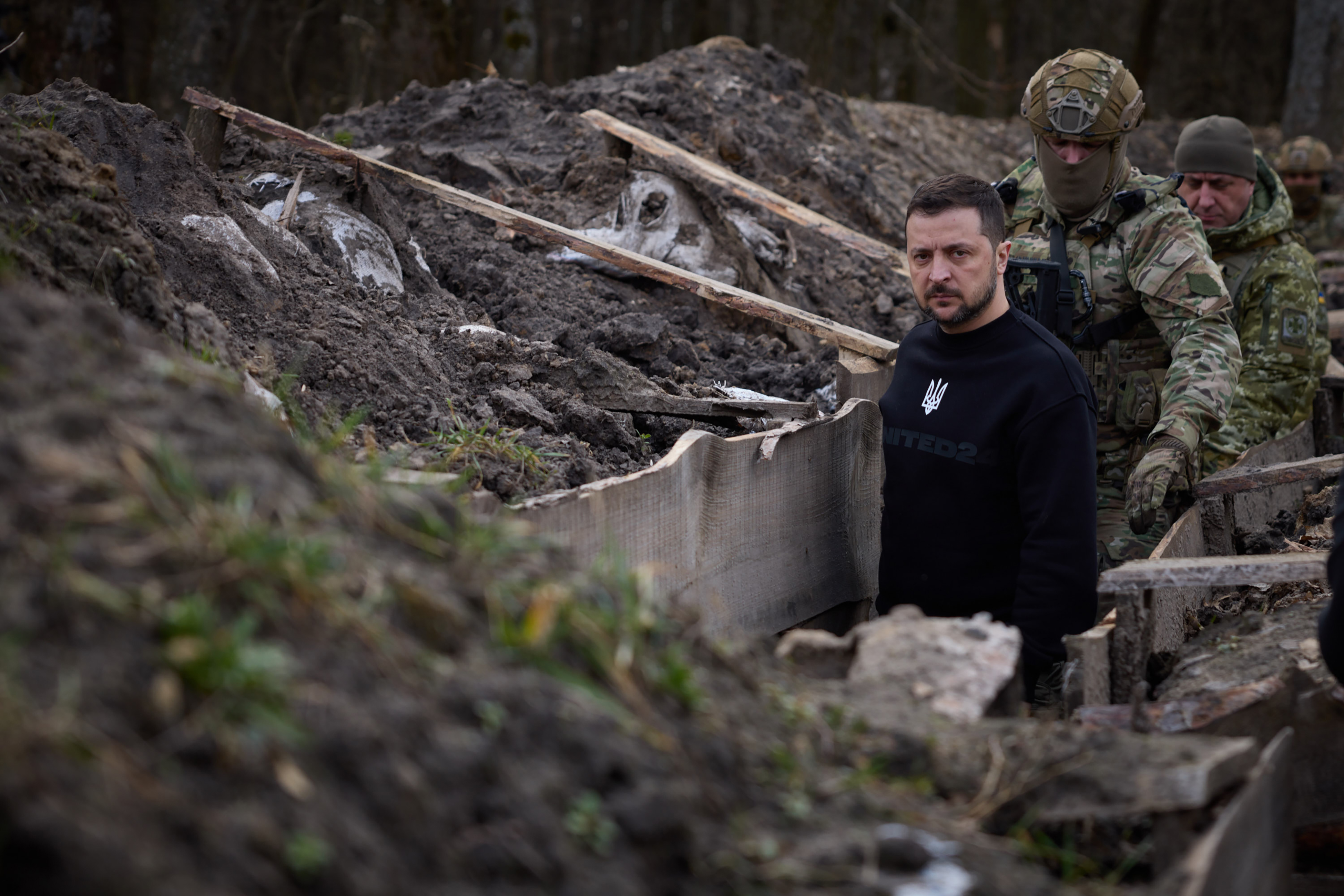 This handout photograph taken and released by the Ukrainian Presidential Press Service on March 28, 2023 shows President Volodymyr Zelenskyy walking along trenches with border guard officers as he inspects the state border with Russian Federation in Ukraine's Sumy region.