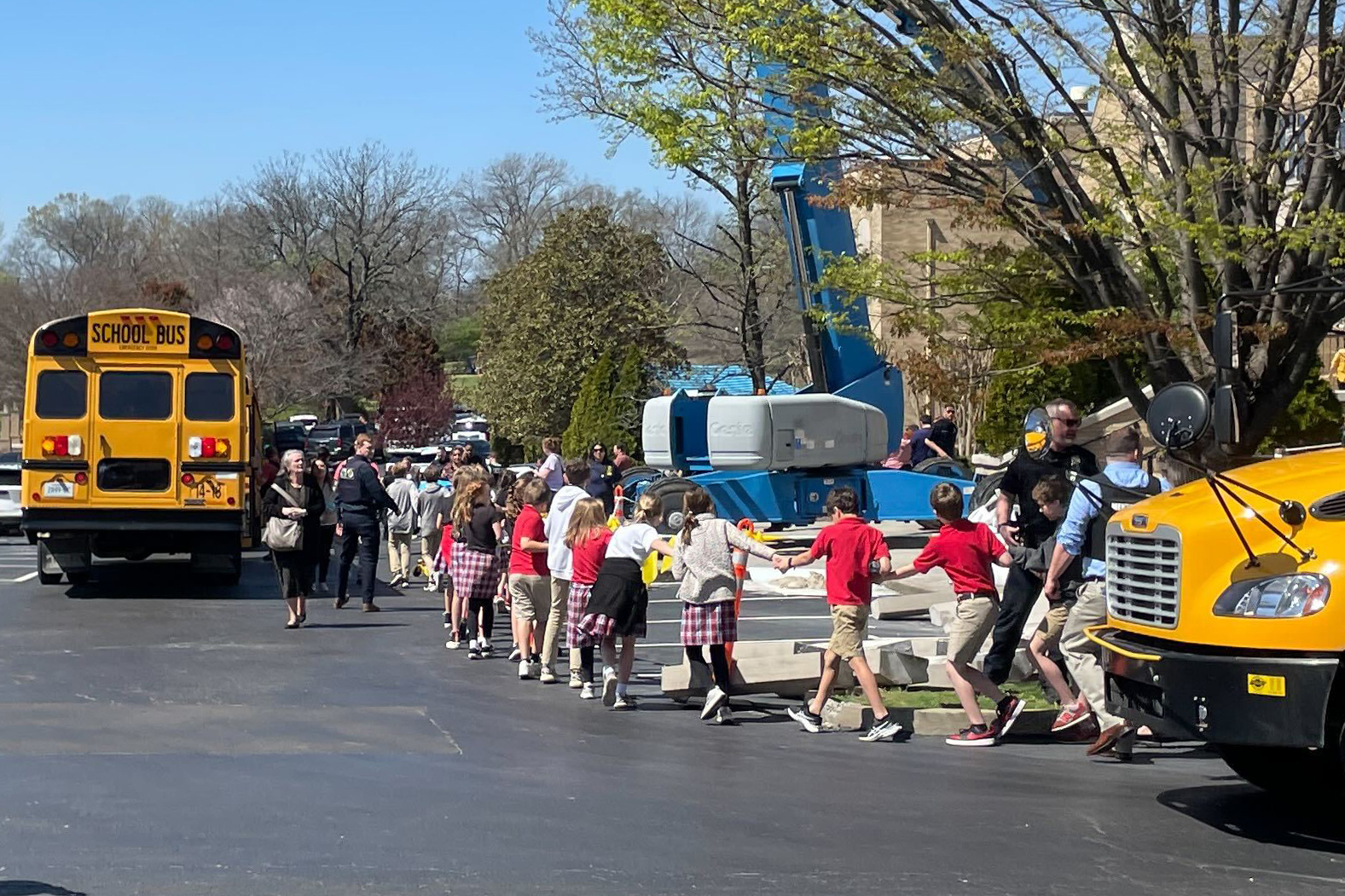 Children from The Covenant School, a private Christian school in Nashville, Tennessee, hold hands as they are taken to a reunification site at the Woodmont Baptist Church after a shooting at their school.