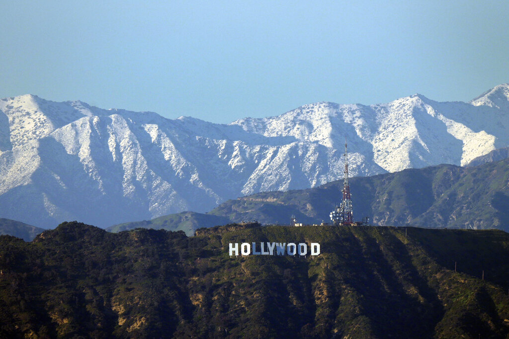 Snowy mountains in the background behind the Hollywood sign in Los Angeles