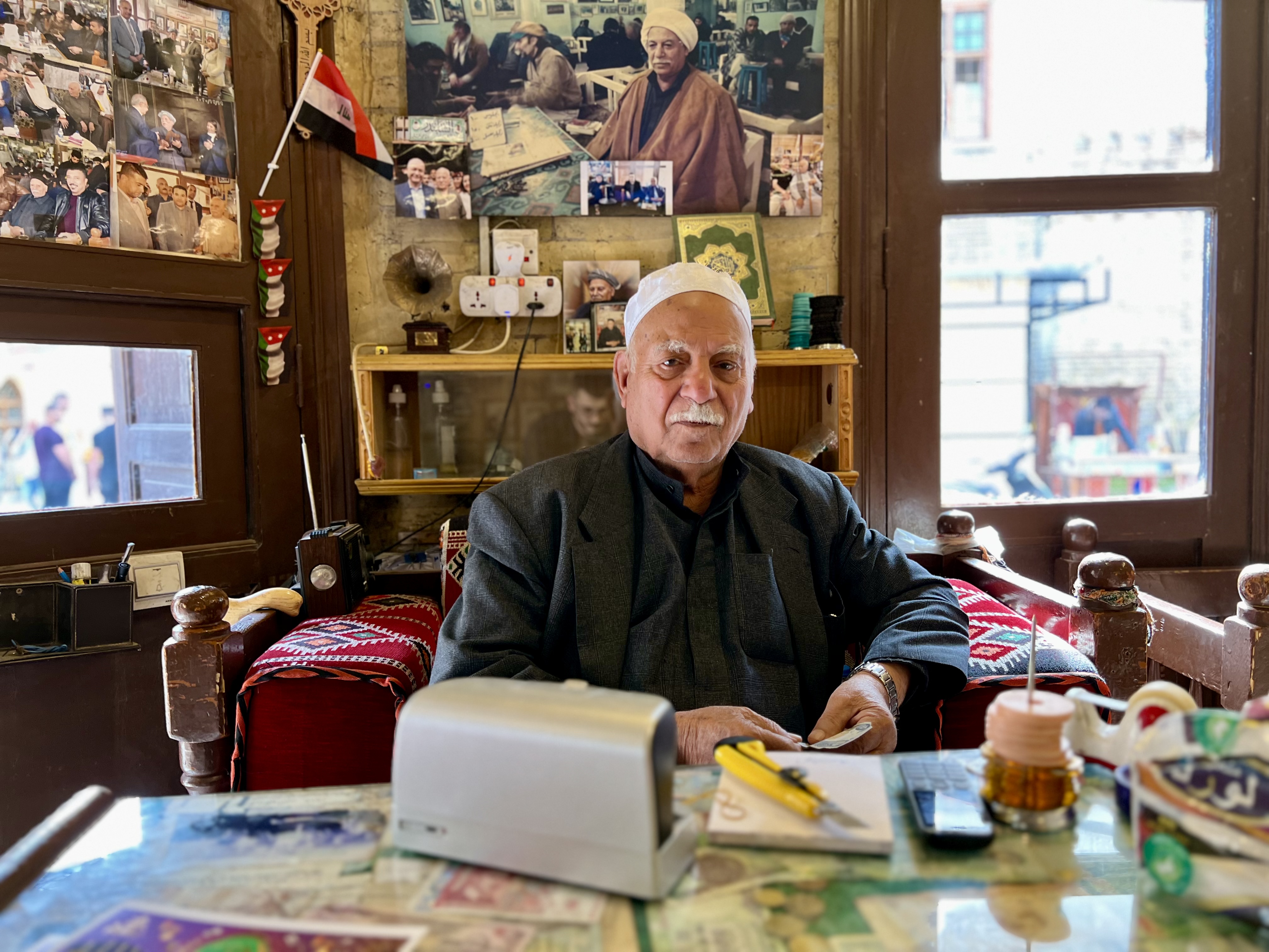 Haj Mohammed al-Khashali behind his desk with photos and mementos of the past behind him. 