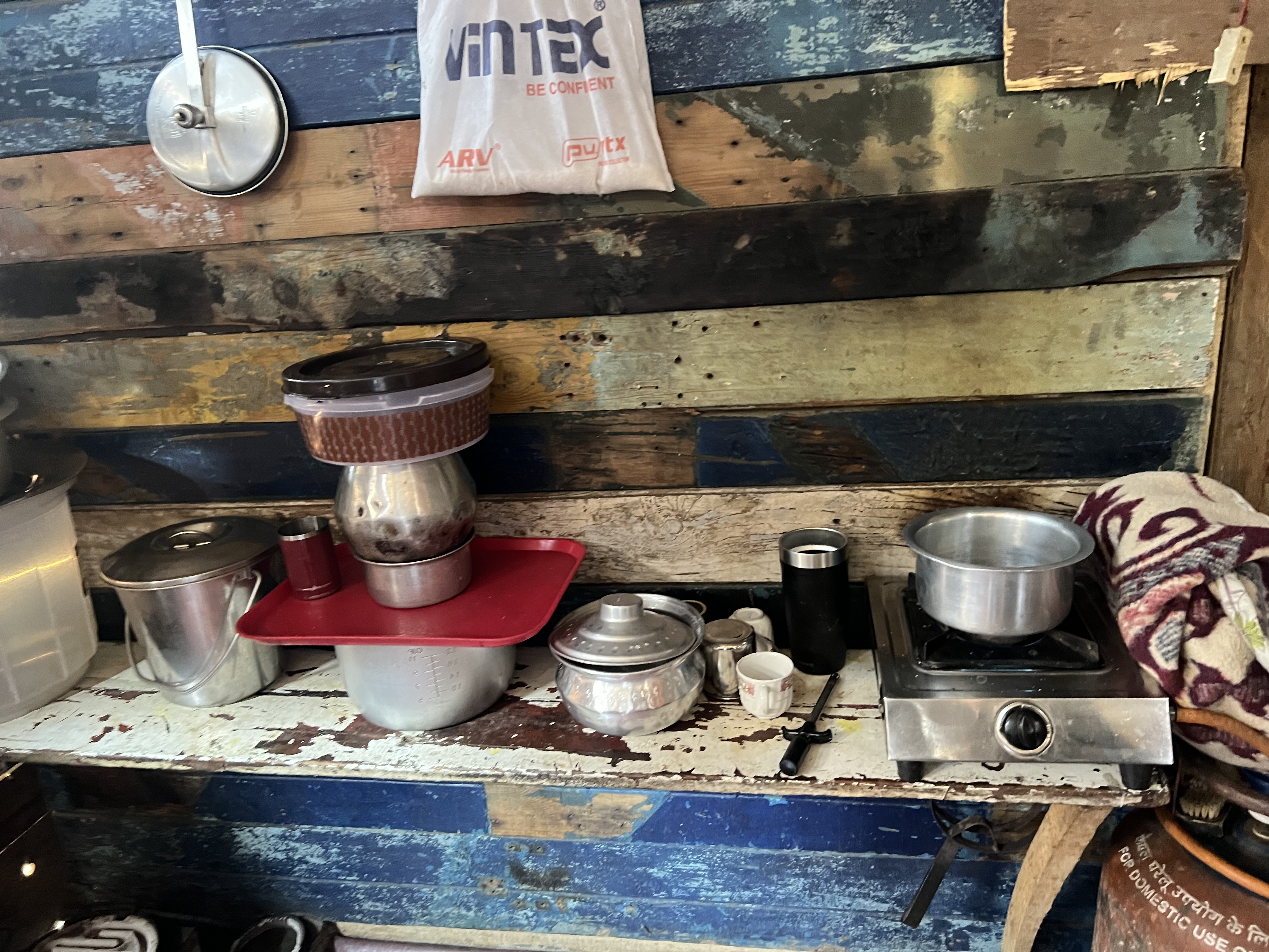 A photo of cooking bowls, pots and pans with a little stove.