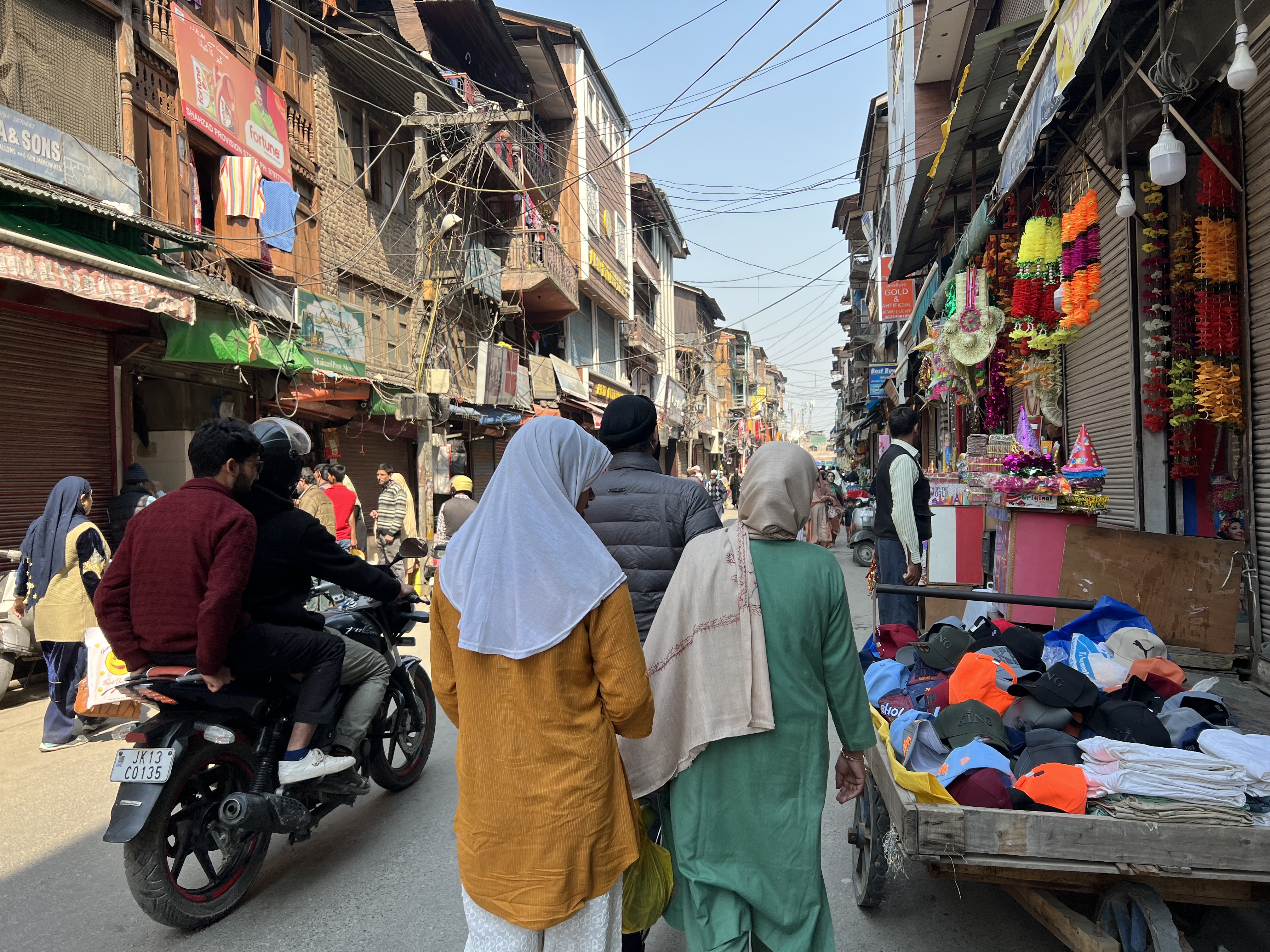 A photo of two people walking through an outdoor market.
