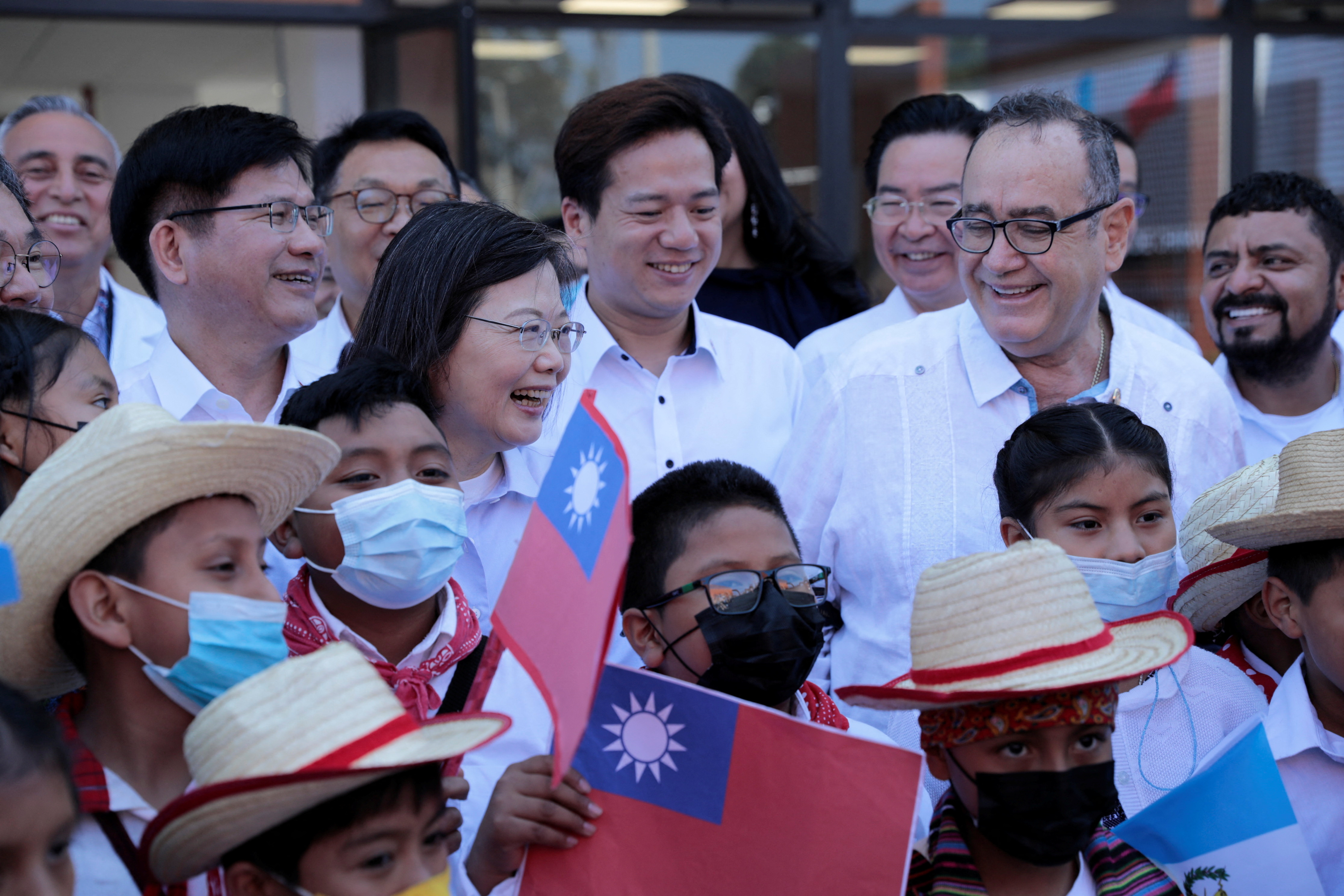 Tsai Ing-wen with children in Guatemala. They are waving Taiwan flags. The president of Guatemala Alejandro Giammattei, is standing next to her.