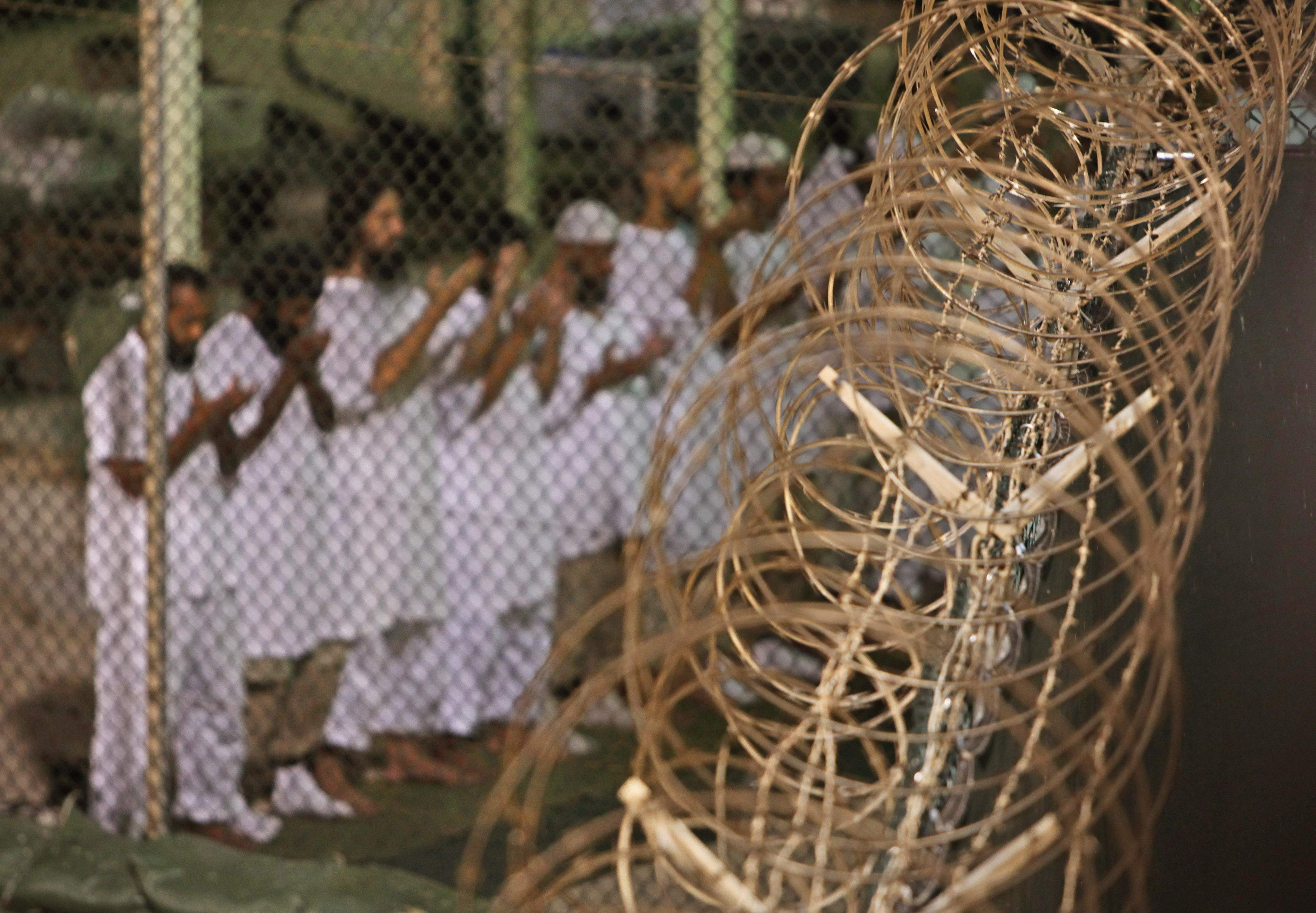 FILE - In this May 14, 2009 file photo, reviewed by the U.S. military, Guantanamo detainees pray before dawn near a fence of razor-wire, inside Camp 4 detention facility at Guantanamo Bay U.S. Naval Base, Cuba. Guards were preparing to serve the first in a series of special meals Wednesday, Aug. 7, 2013, to prisoners at Guantanamo Bay to mark the end of the Muslim holy period of Ramadan. There will also be a special hour-long prayer for the holiday known as Eid al-Fitr in addition to the five daily prayers. (AP Photo/Brennan Linsley, File)