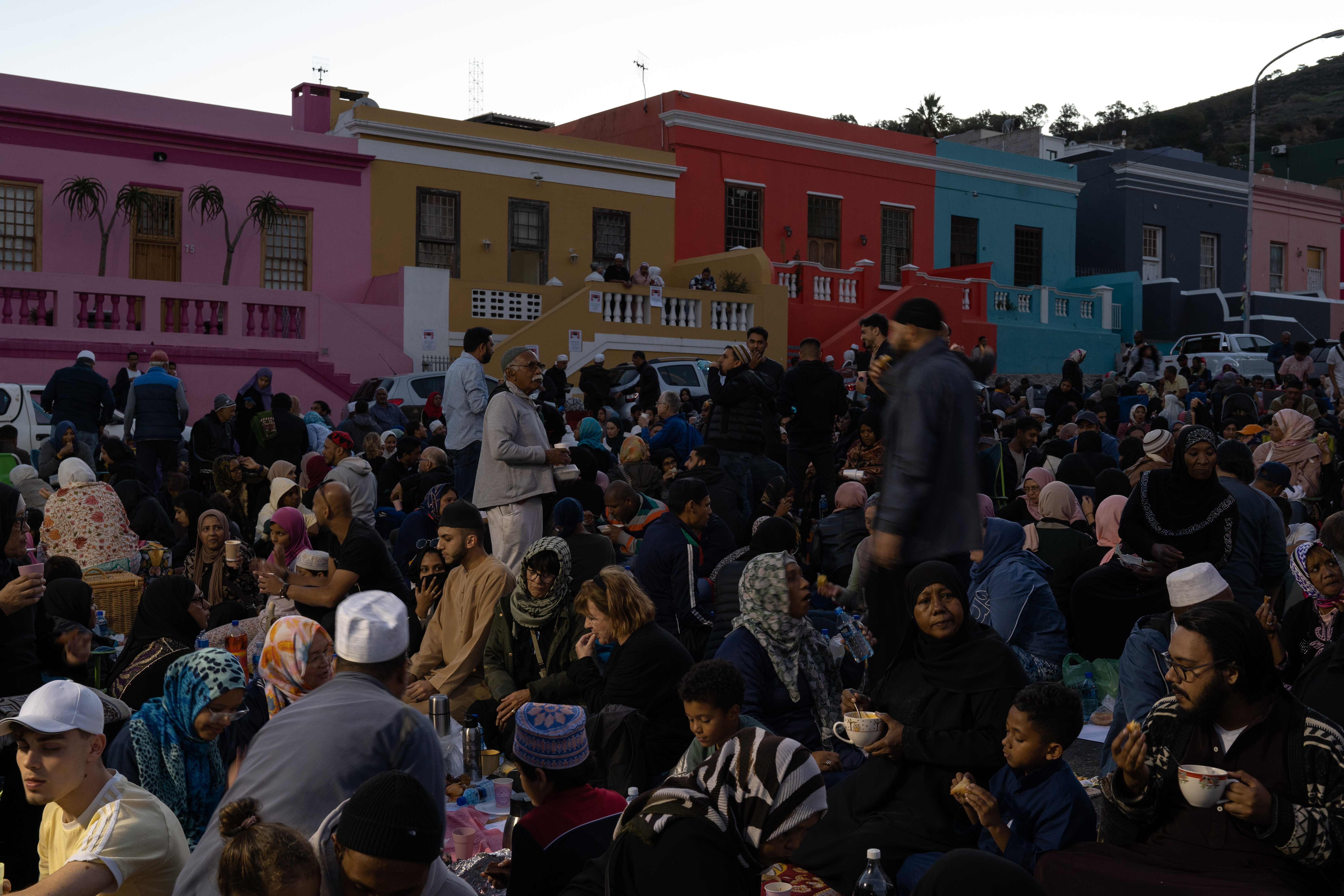 A photo of a large crowd of people with colourful buildings in the background.