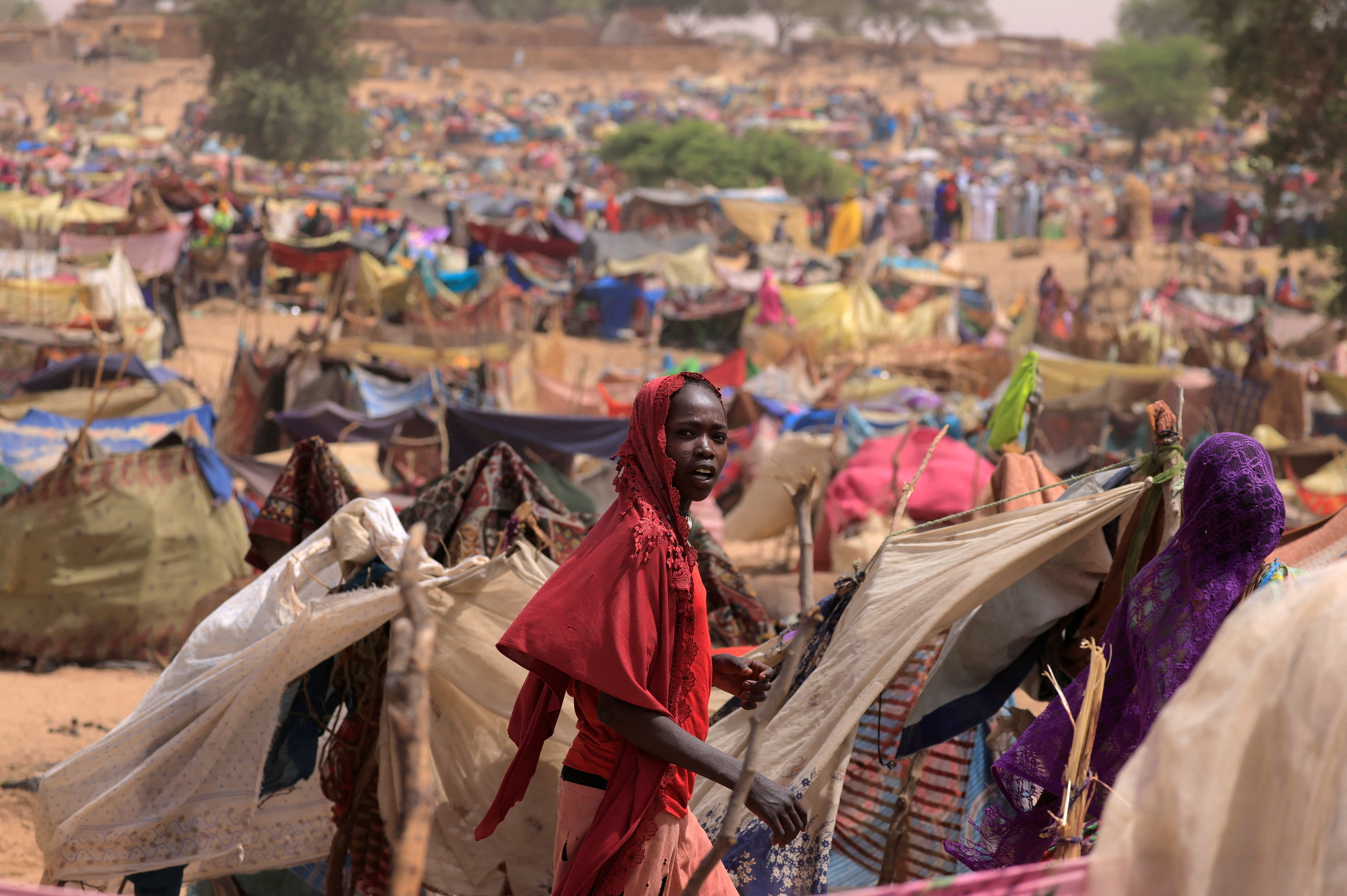 A Sudanese girl who fled the conflict in Sudan's Darfur region, and was previously internally displaced in Sudan, moves past makeshift shelters, near the border between Sudan and Chad
