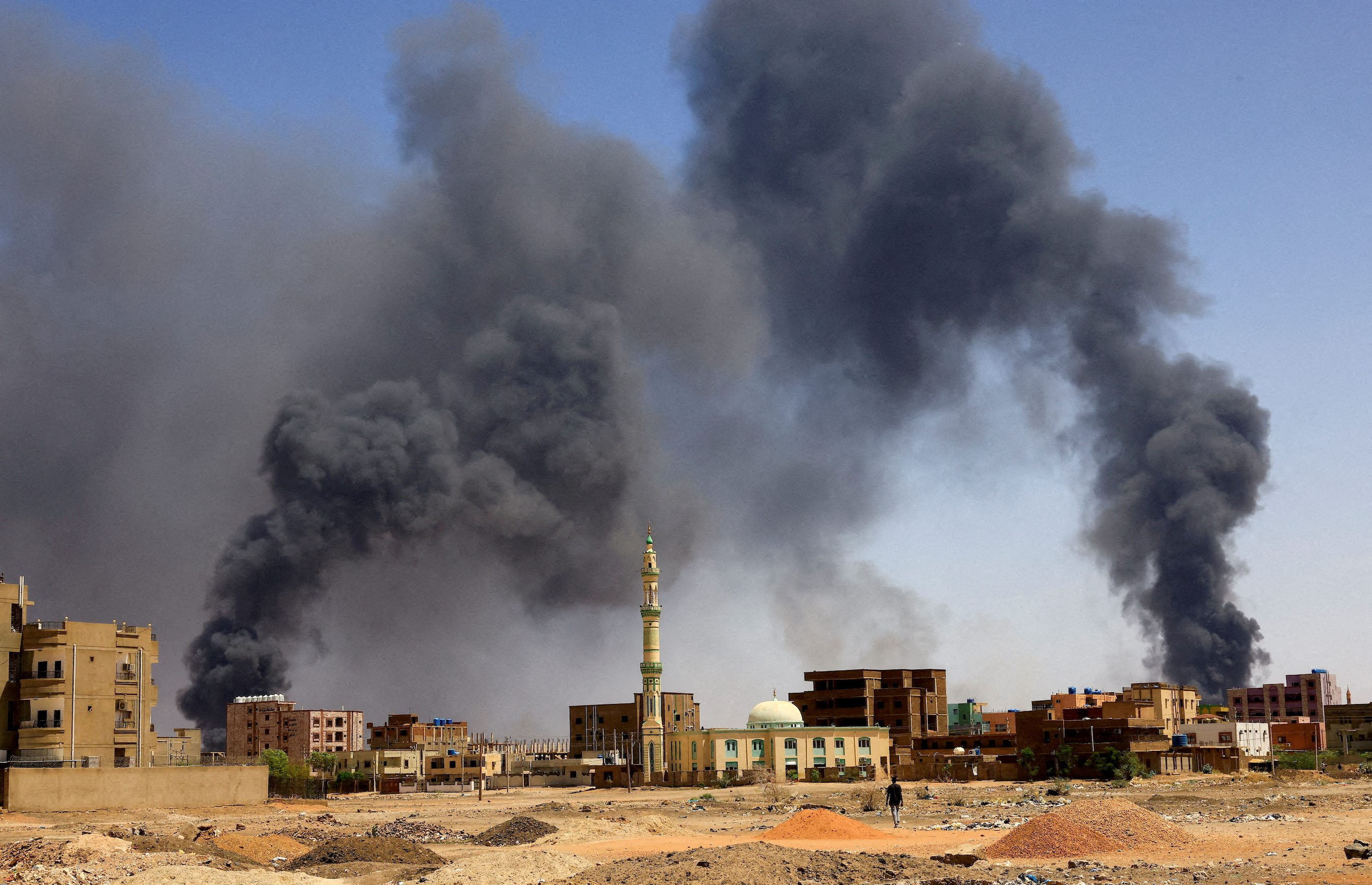 FILE PHOTO: A man walks while smoke rises above buildings after aerial bombardment, during clashes between the paramilitary Rapid Support Forces and the army in Khartoum North, Sudan, May 1, 2023.
