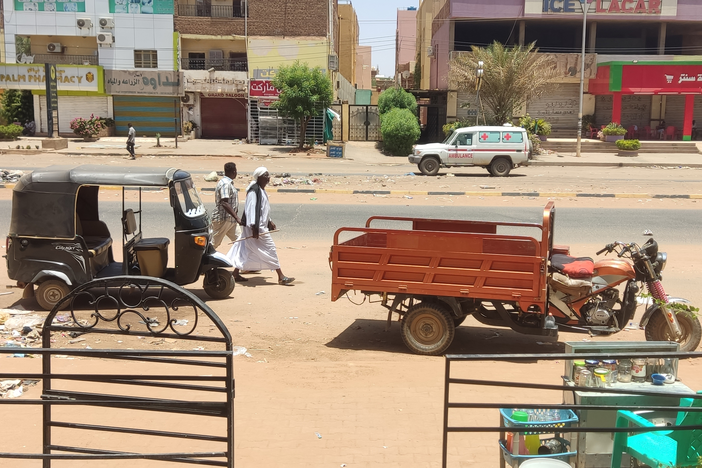 People walk past parked three-wheeled vehicles on al-Sittin (sixty) road in Khartoum