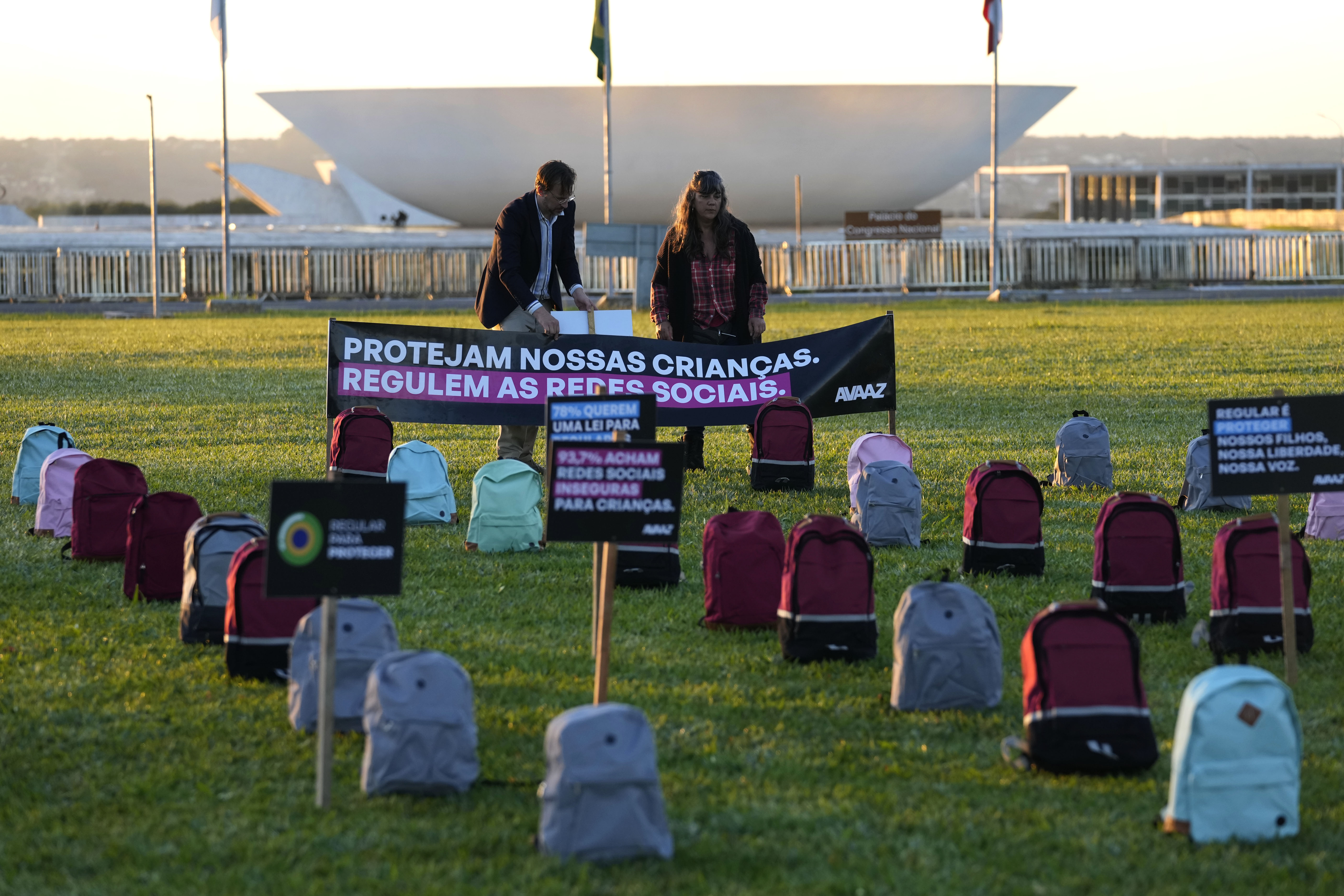 Protesters outside Brazil's congress place signs and backpacks on the grass to represent children killed in school attacks