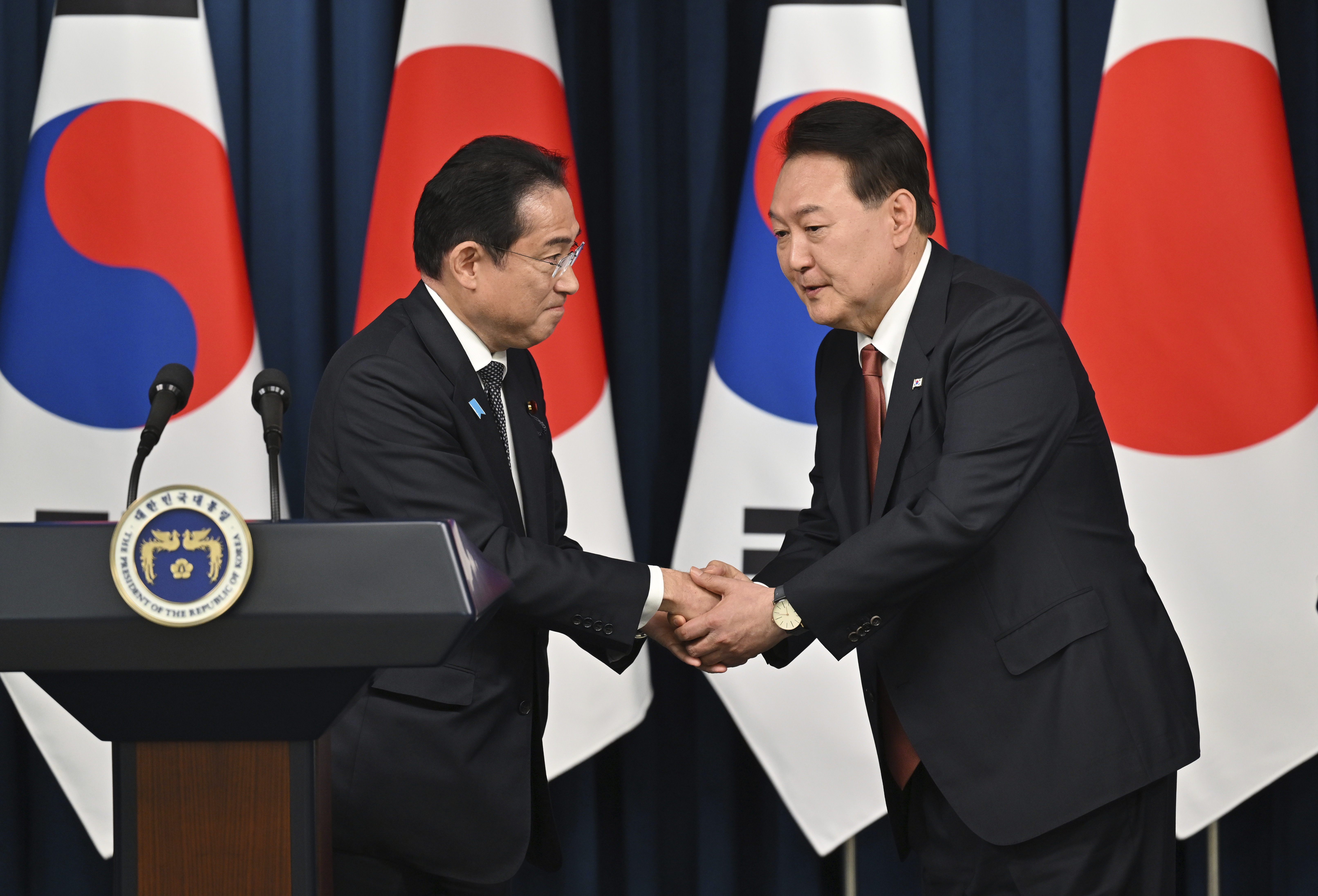 South Korean President Yoon Suk Yeol, right, shakes hands with Japanese Prime Minister Fumio Kishida during a joint press conference after their meeting at the presidential office in Seoul