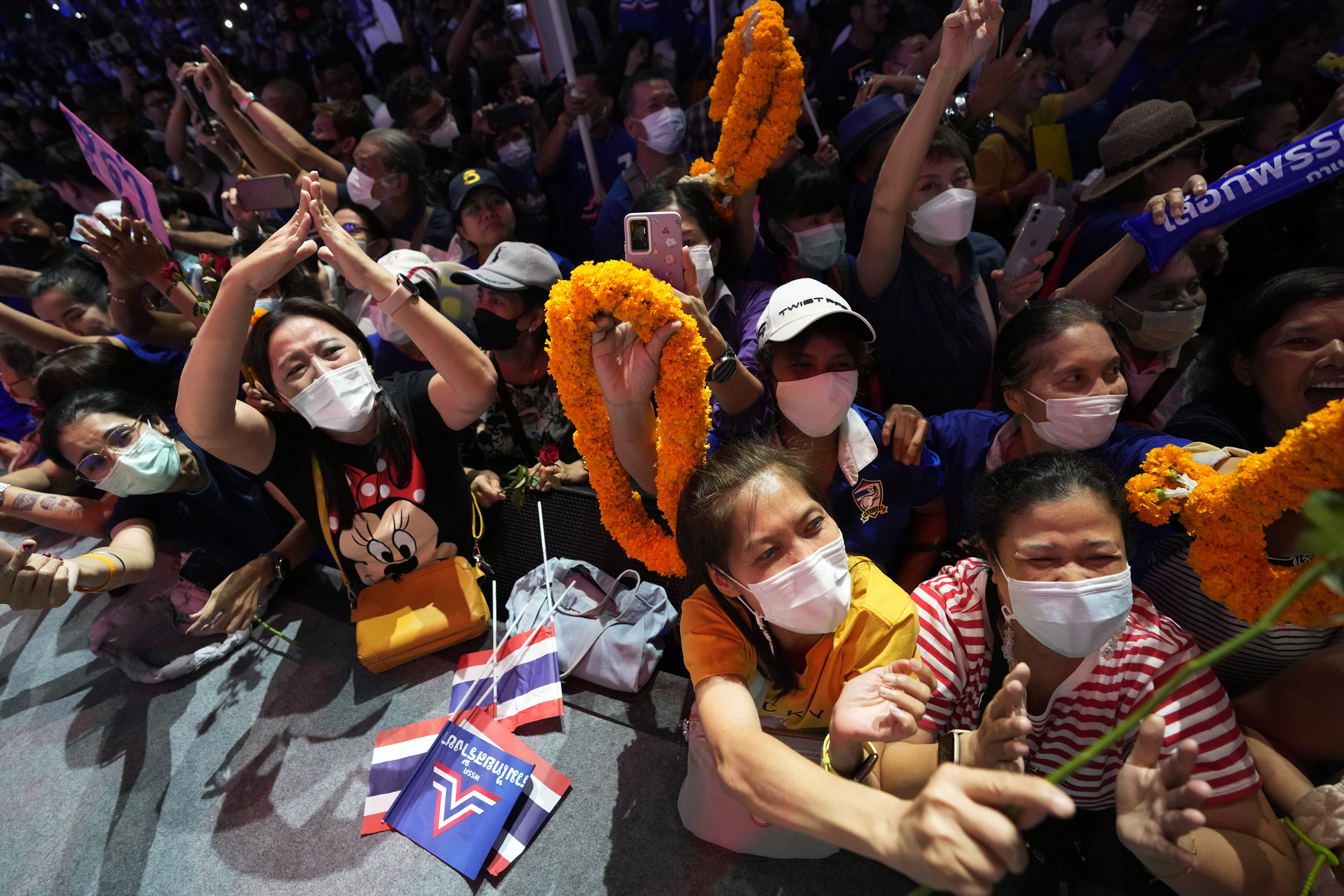 Supporters of Prayuth Chan-ocha cheer in the party's final election really. They have small Thai flags and garlands of marigolds