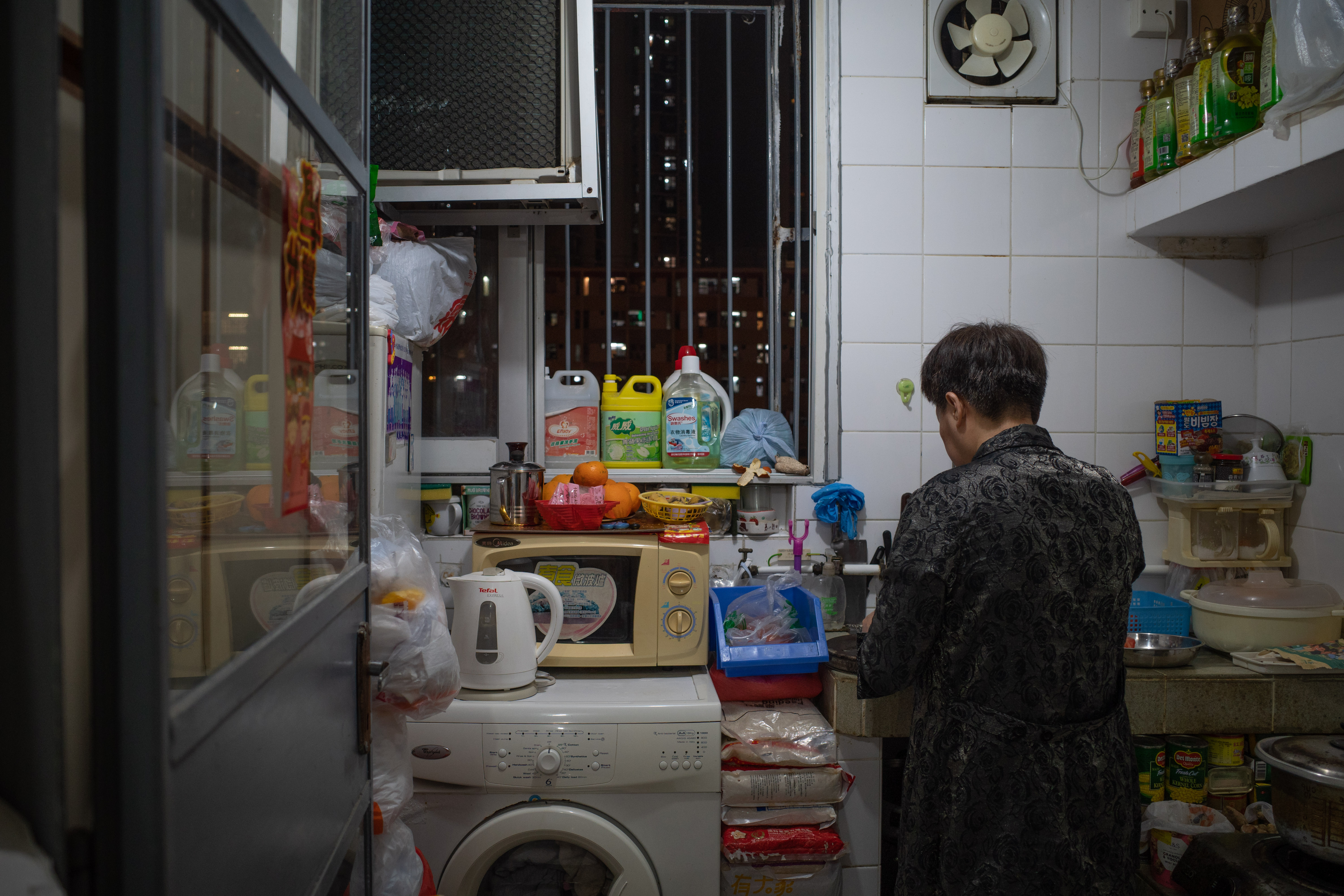 Mrs Chan in the cramped kitchen of her family's rented apartment that is just 23 square metres (248 square feet). Foodstuffs and cleaning products can be seen arranged in every nook and cranny available.
