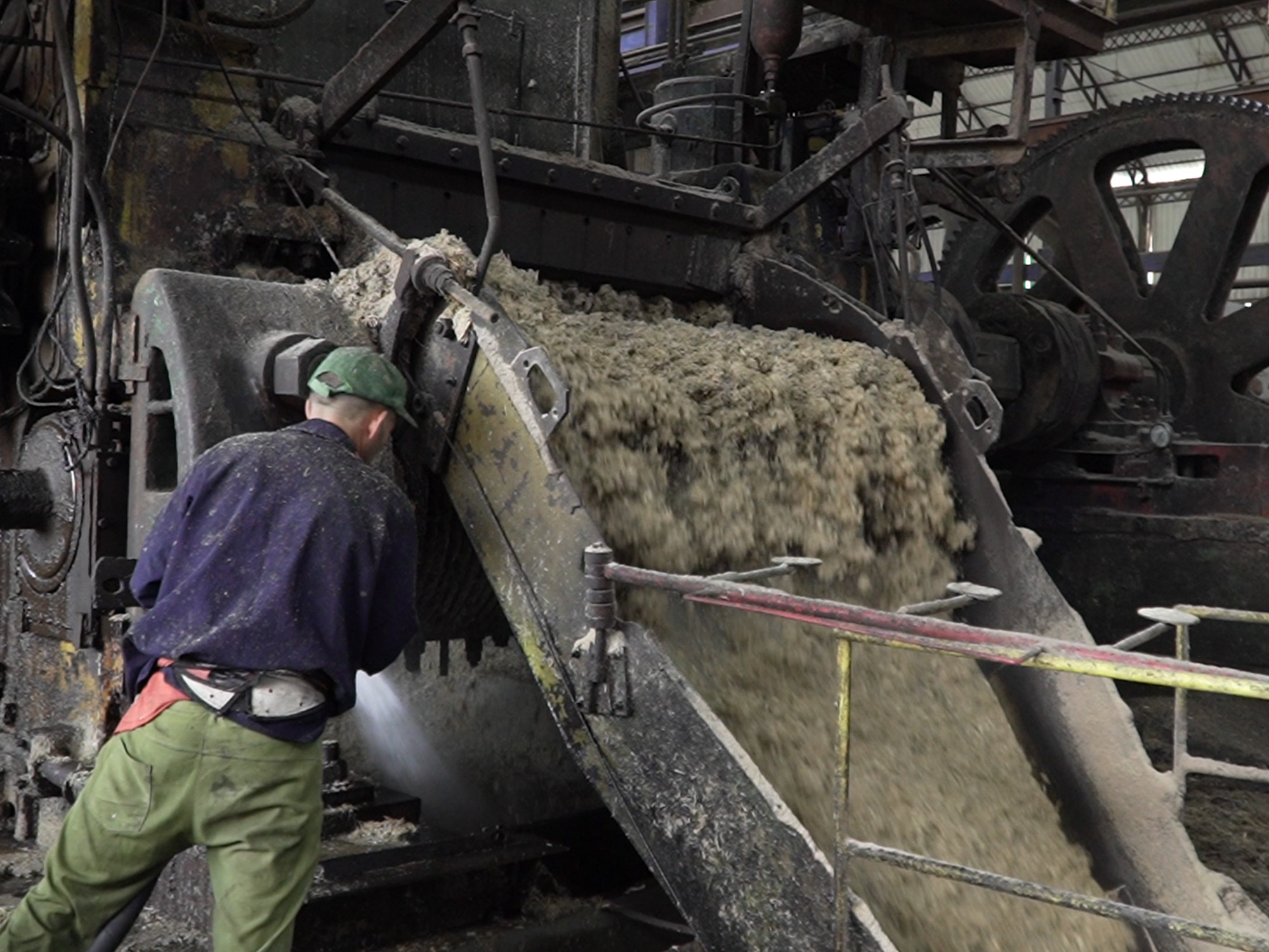 A man stands watch over a sugar-cane press at a factory