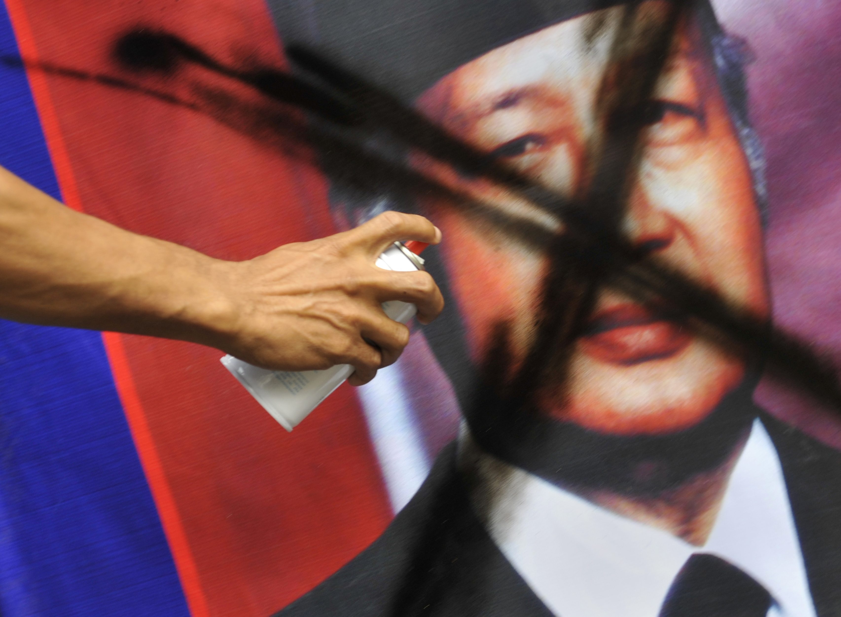 A banner bearing the portrait of Soeharto is vandalised by a demonstrator.