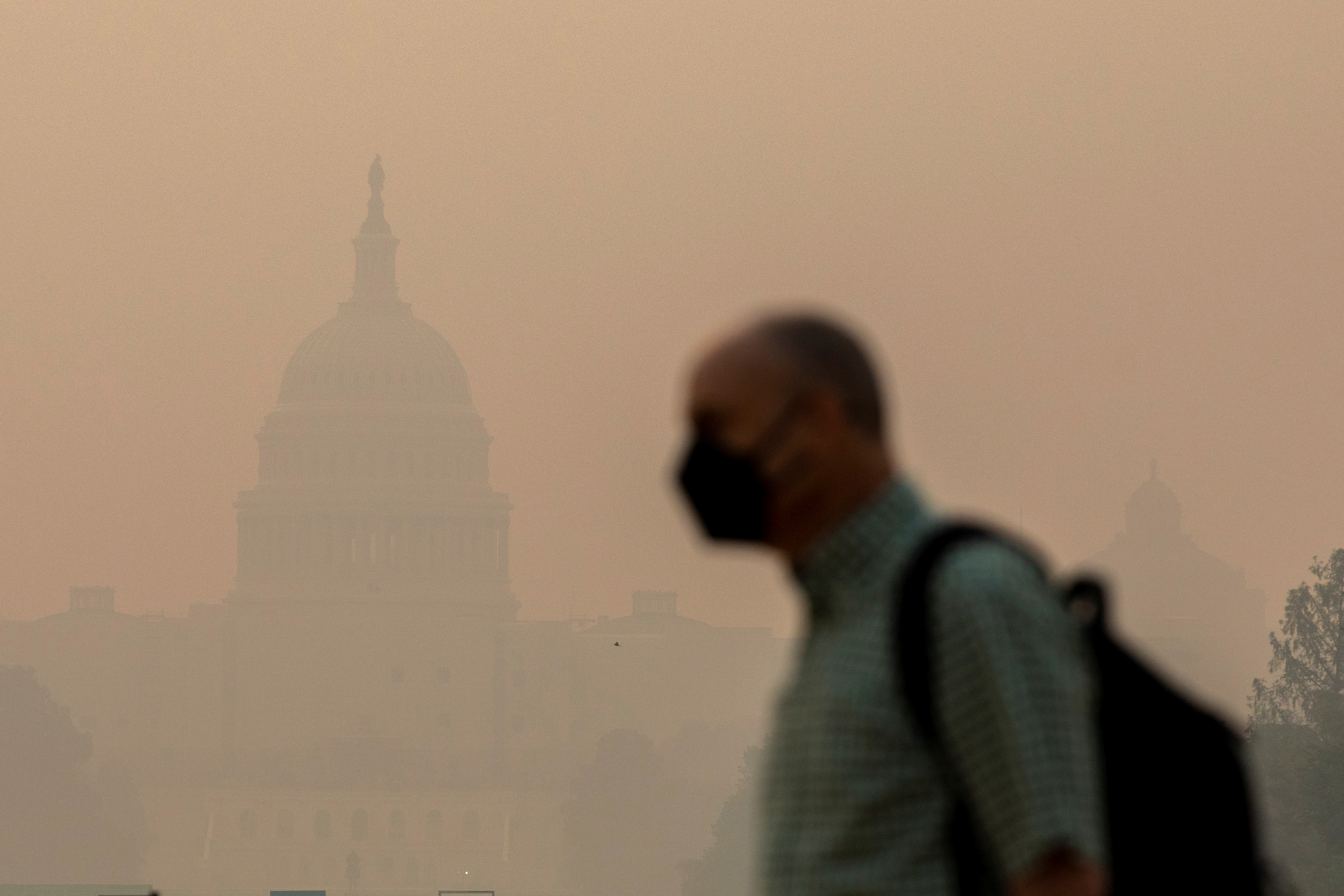A man walks past the US Capitol shrouded in a cloud of smoke