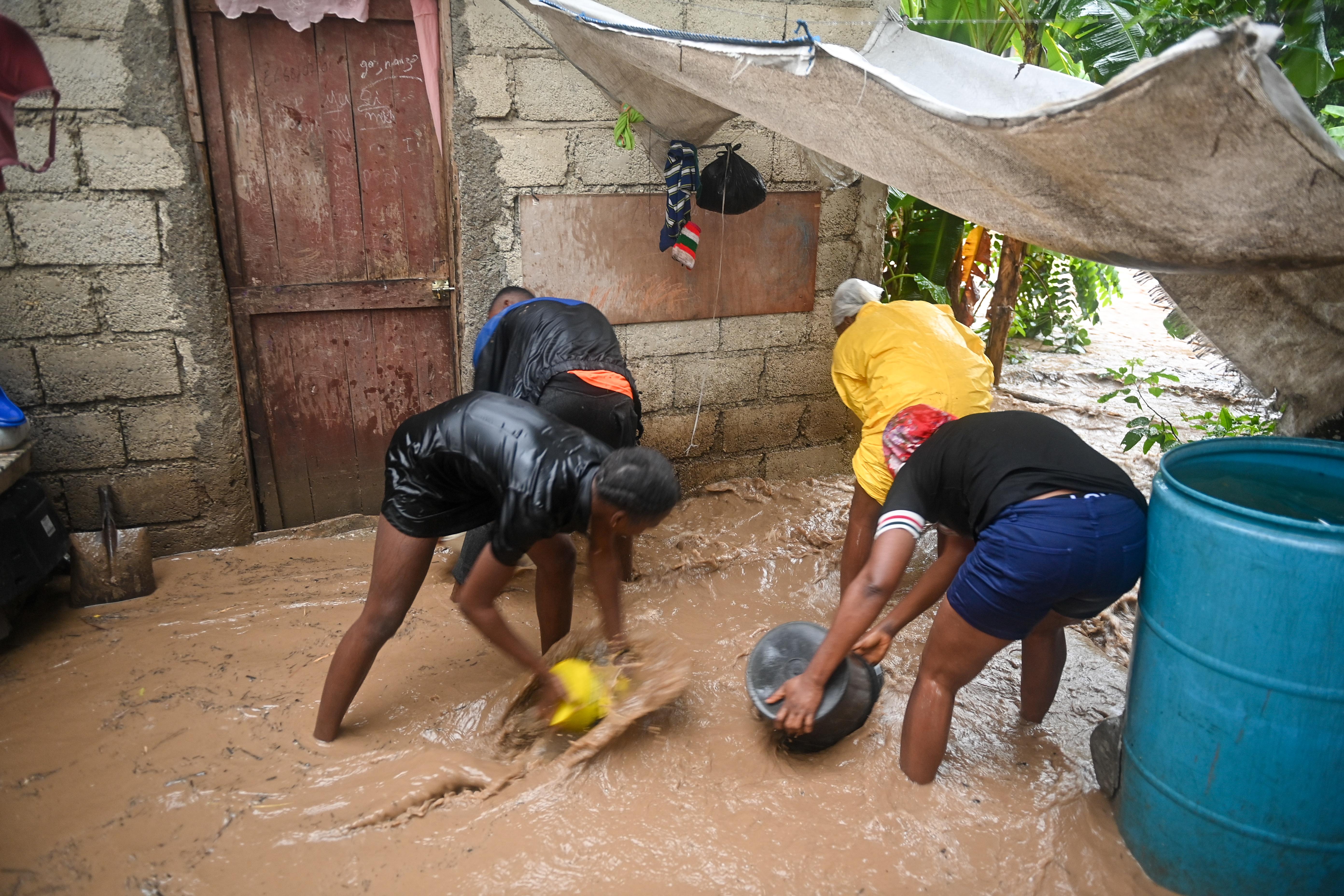 Resident bail flood water in front of a home in Petit-Goâve, Haiti