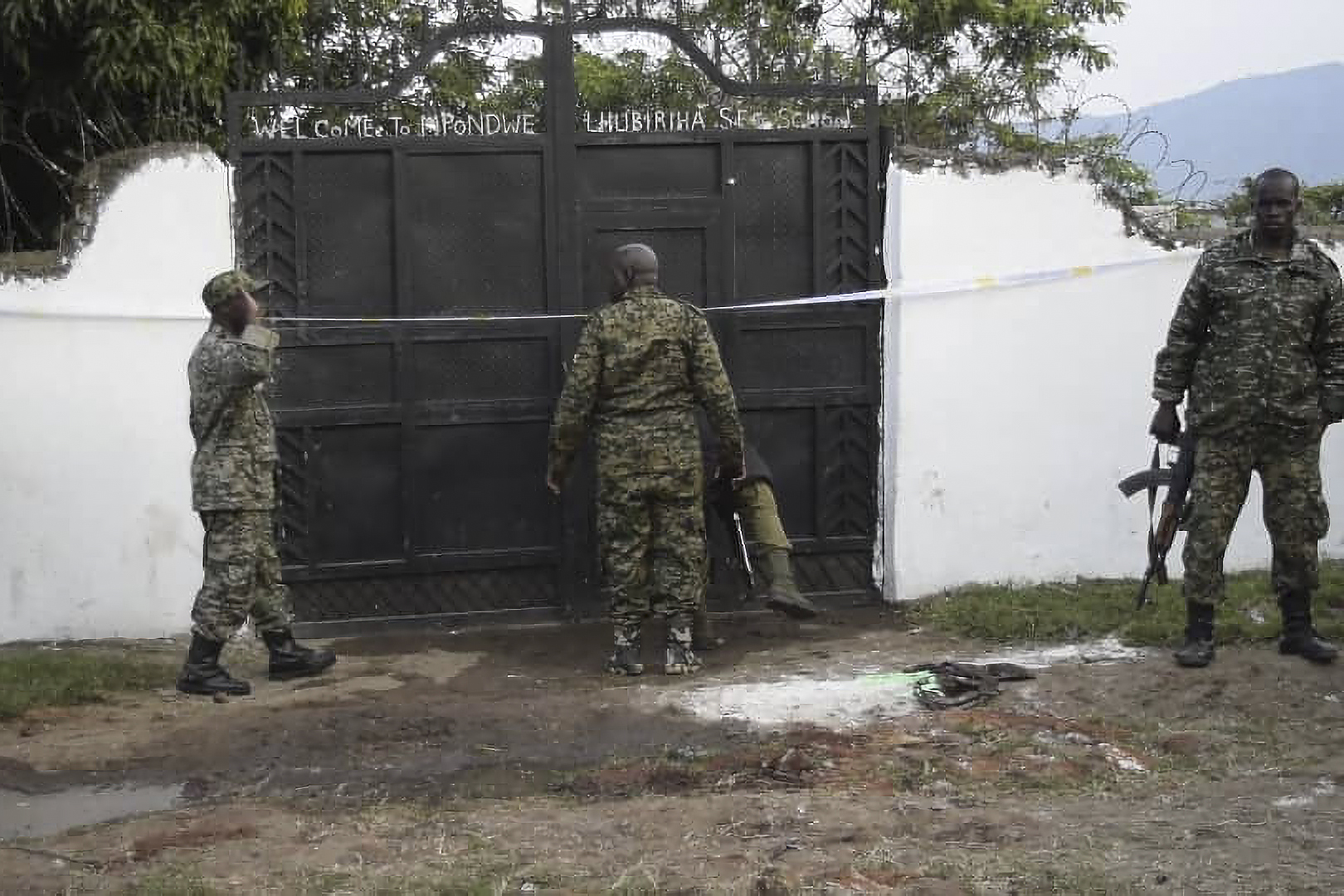 Uganda security forces are seen standing at the premises of an attack in Mpondwe