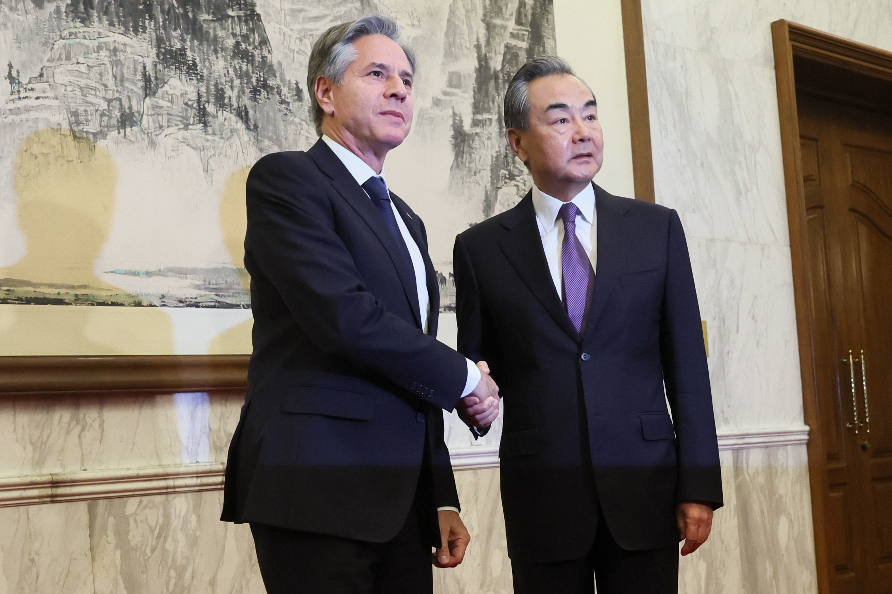 Antony Blinken and Wang Yi shaking hands. They look cordial. There's a traditional Chinese painting behind them.