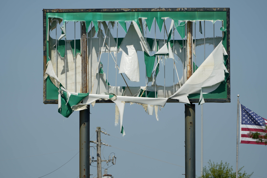A tattered sign shows the aftermath of a tornado