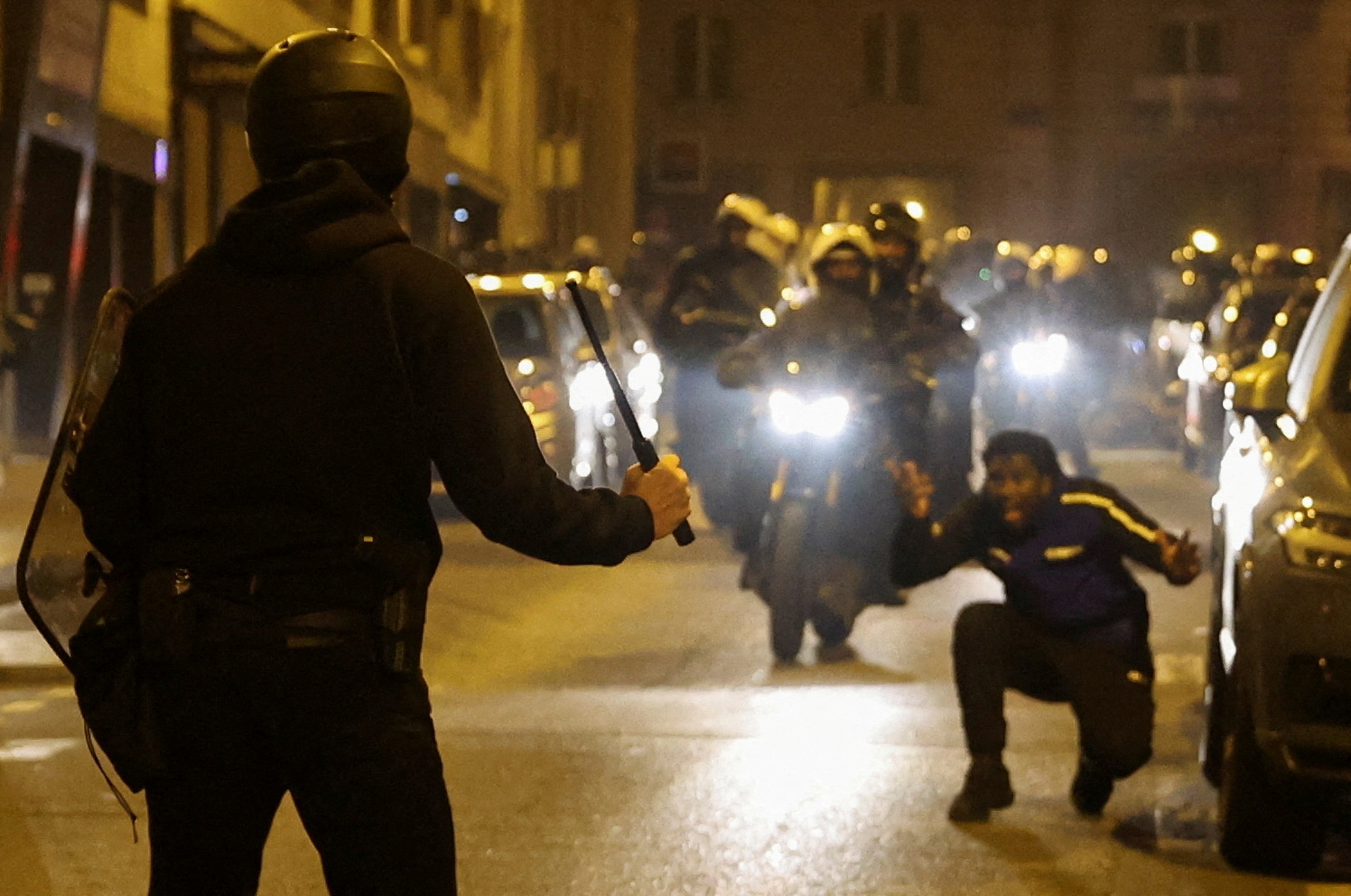 A person reacts while a police officer holds a baton during protests following the death of Nahel, a 17-year-old teenager killed by a French police officer in Nanterre during a traffic stop