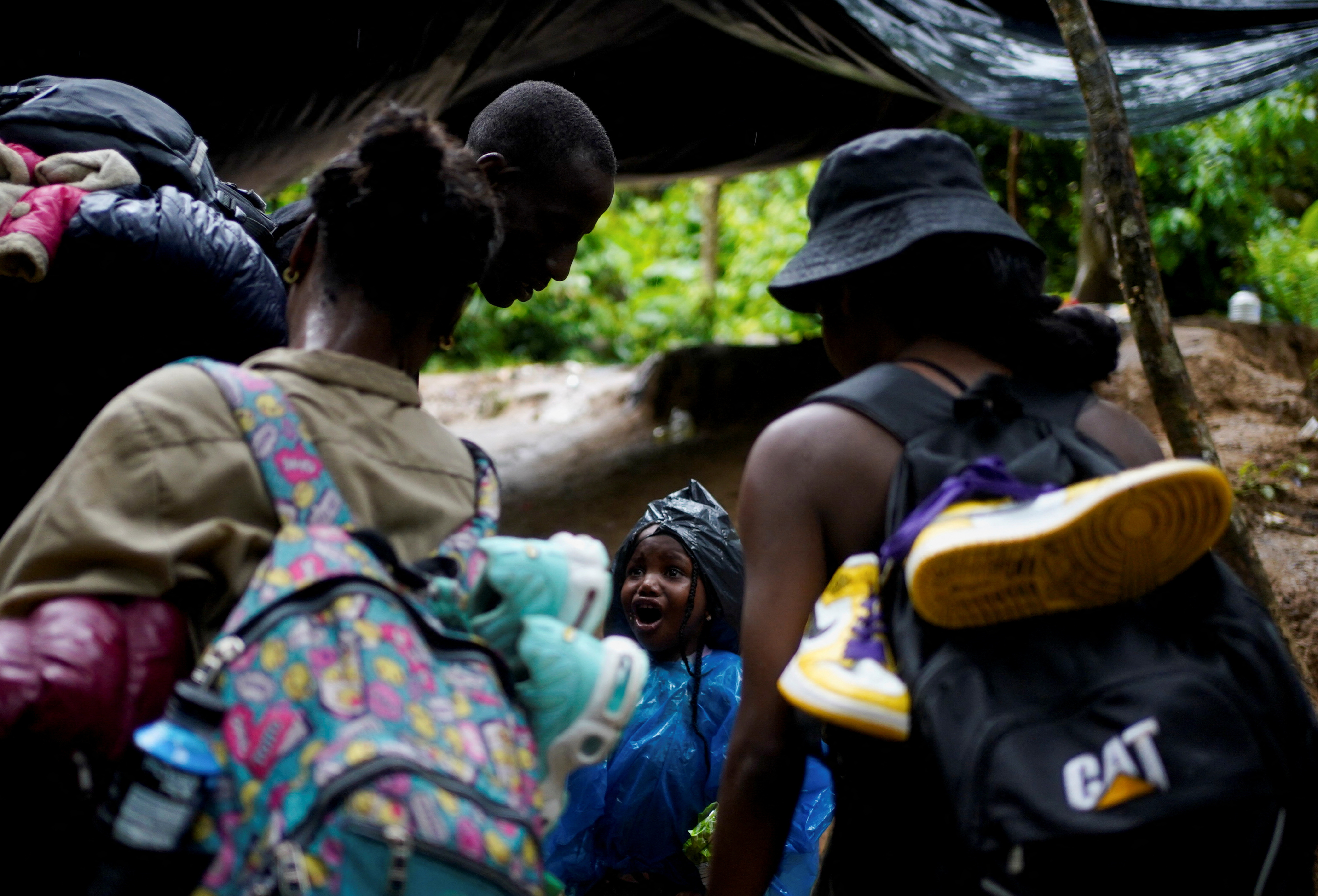 A migrant child from Haiti gestures to her parents