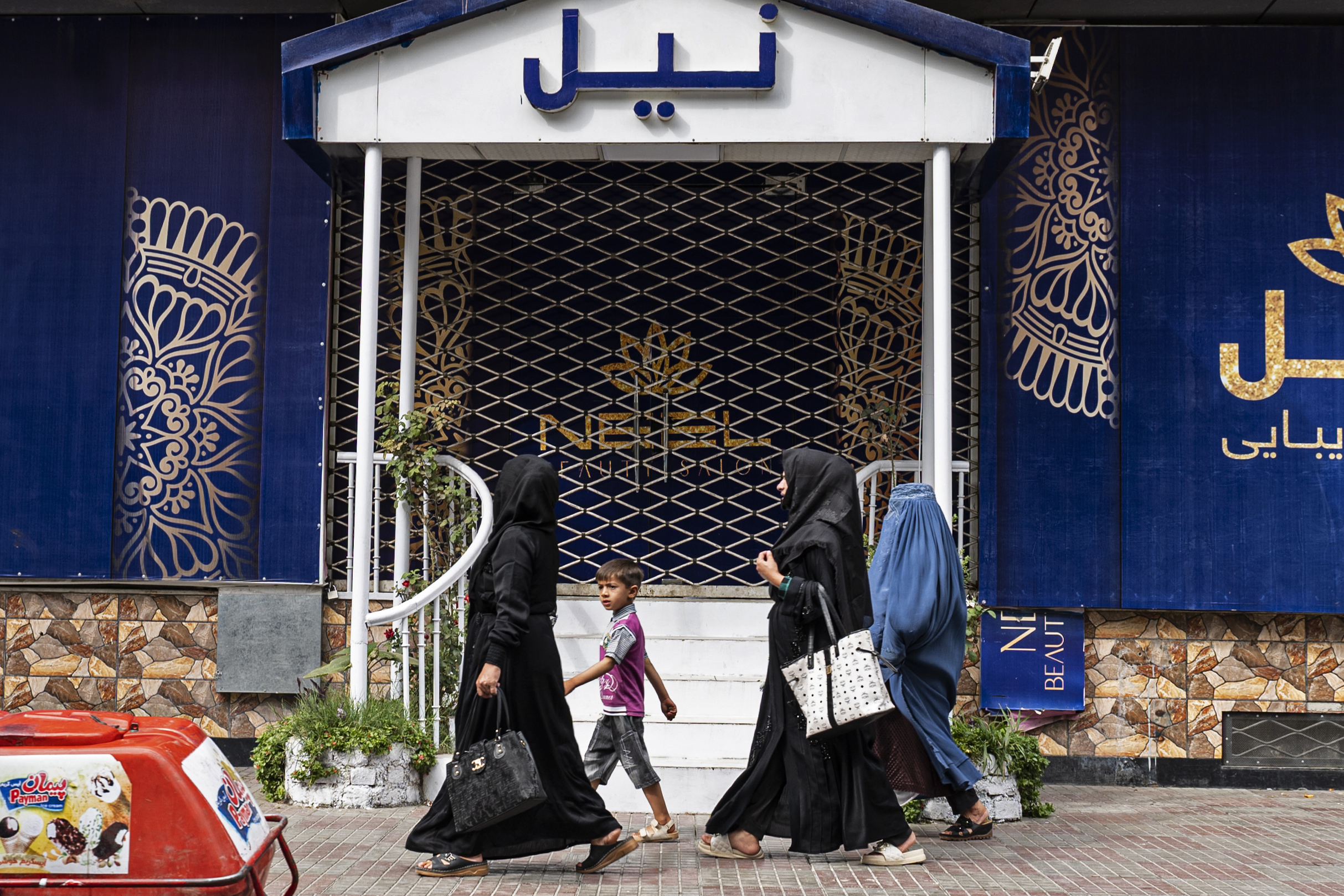 Afghan women walks past a closed beauty parlour in Kabul