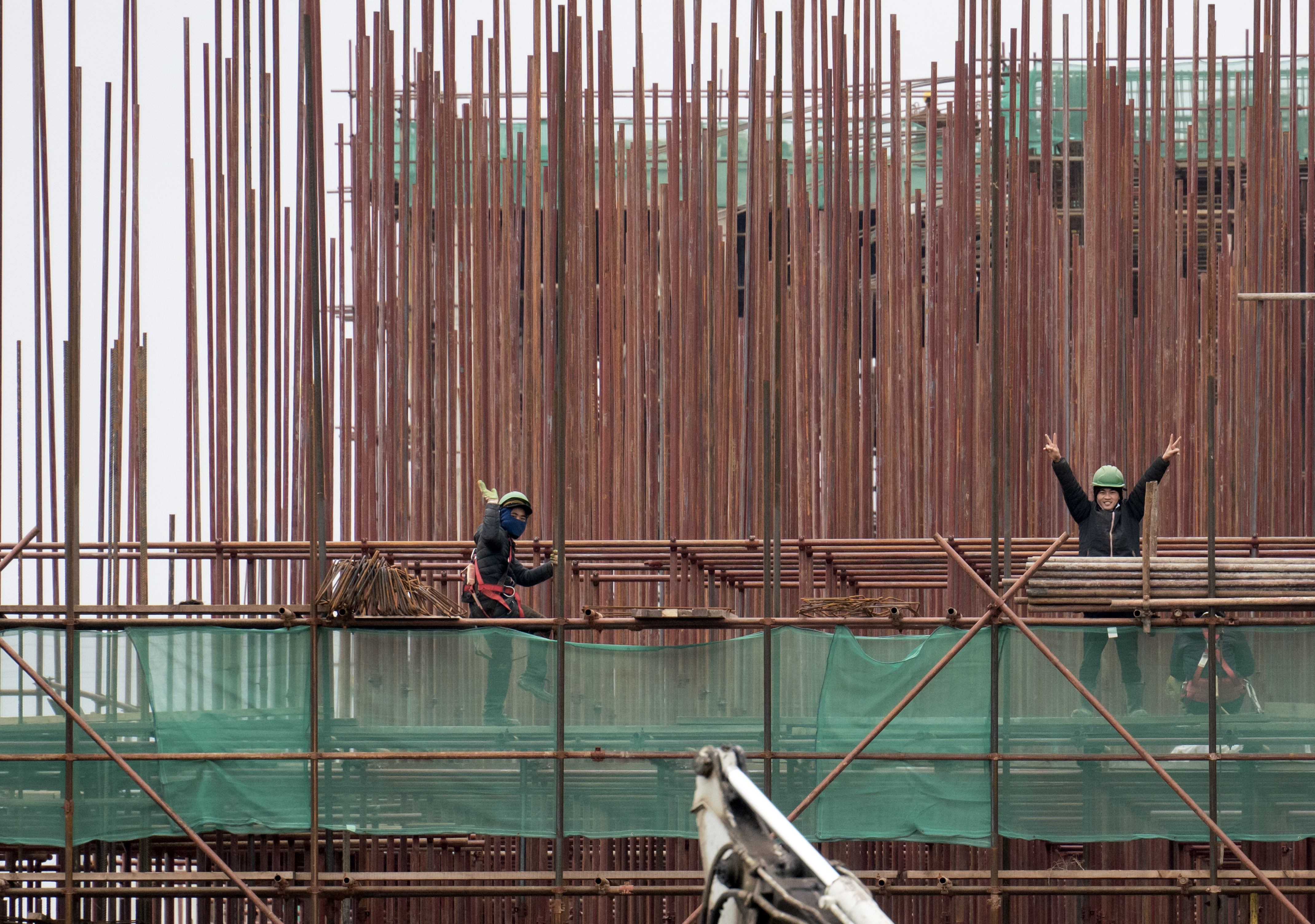 Vietnamese workers wave as they work at the construction site of Chinese tyre factory Linglong near Zrenjanin, on November, 19 2021. - Some 500 Vietnamese workers went on strike last week, claiming they were unable to leave the company after being placed without heating, electricity and drinking water in dilapidated quarters of an abandoned factory. This was the third time in less than six months Vietnamese workers went on strike according to the report, first two were because of lack of food and unpaid salaries. (Photo by OLIVER BUNIC / AFP)