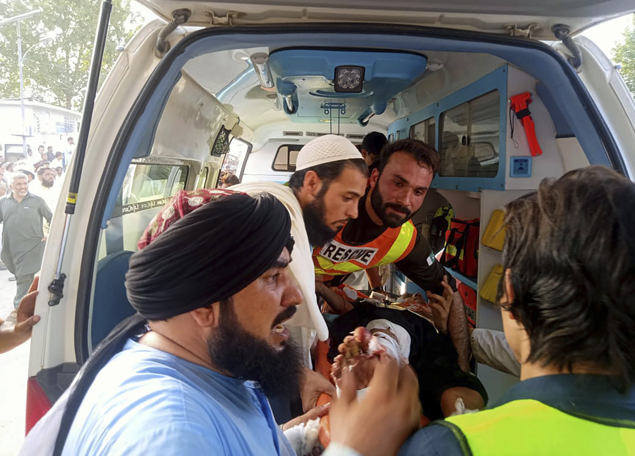 In this photo provided by Rescue 1122 Head Quarters, rescue workers carry a wounded man after a bomb explosion in the Bajur district of Khyber Pakhtunkhwa
