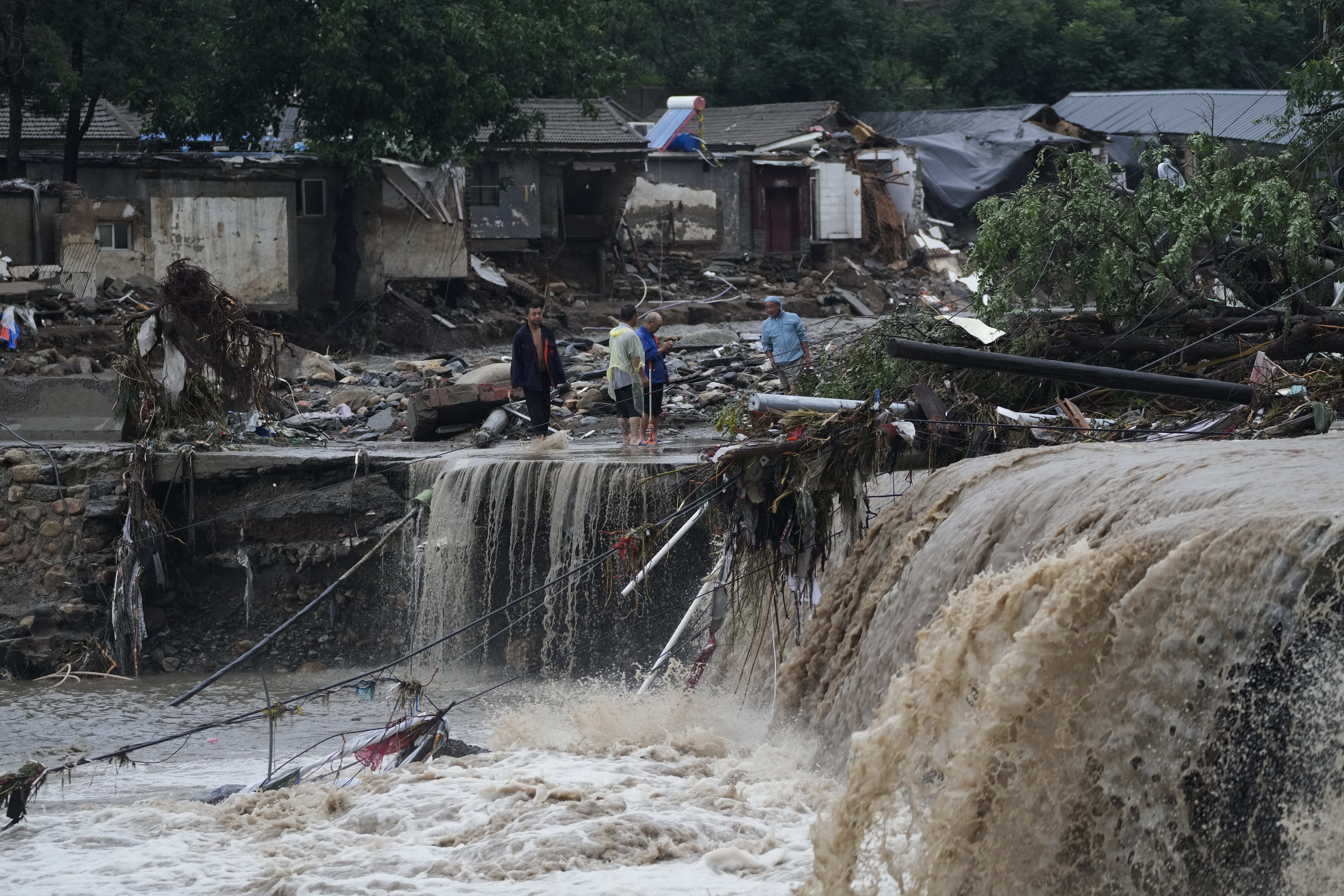 Villagers gather near a village damaged by floodwaters