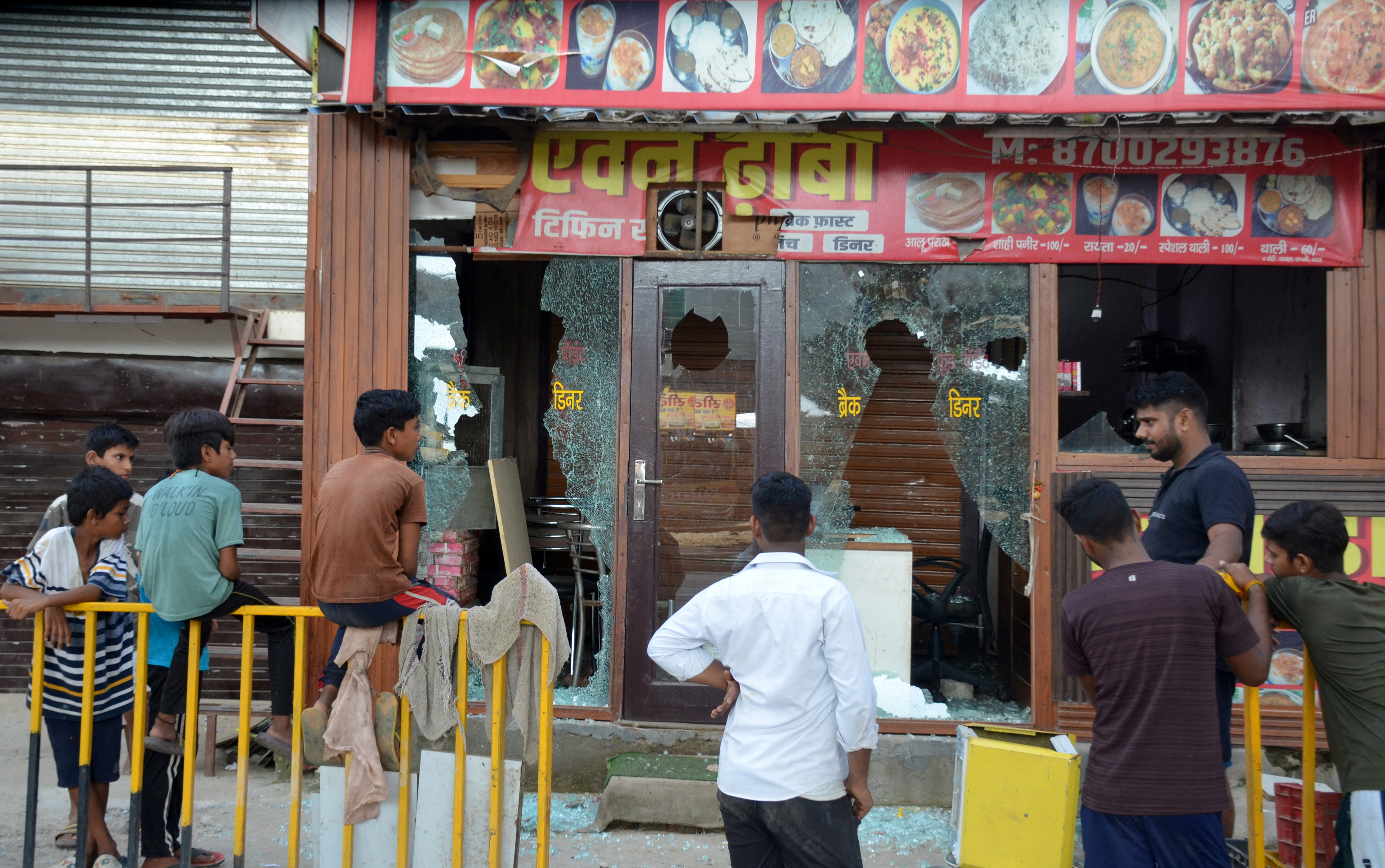 People stand in front of an eatery after it was vandalised by a mob following clashes between Hindu and Muslims that erupted on Monday, in Gurugram, on the outskirts of New Delhi, India, August 1, 2023. REUTERS/Stringer NO RESALES. NO ARCHIVES